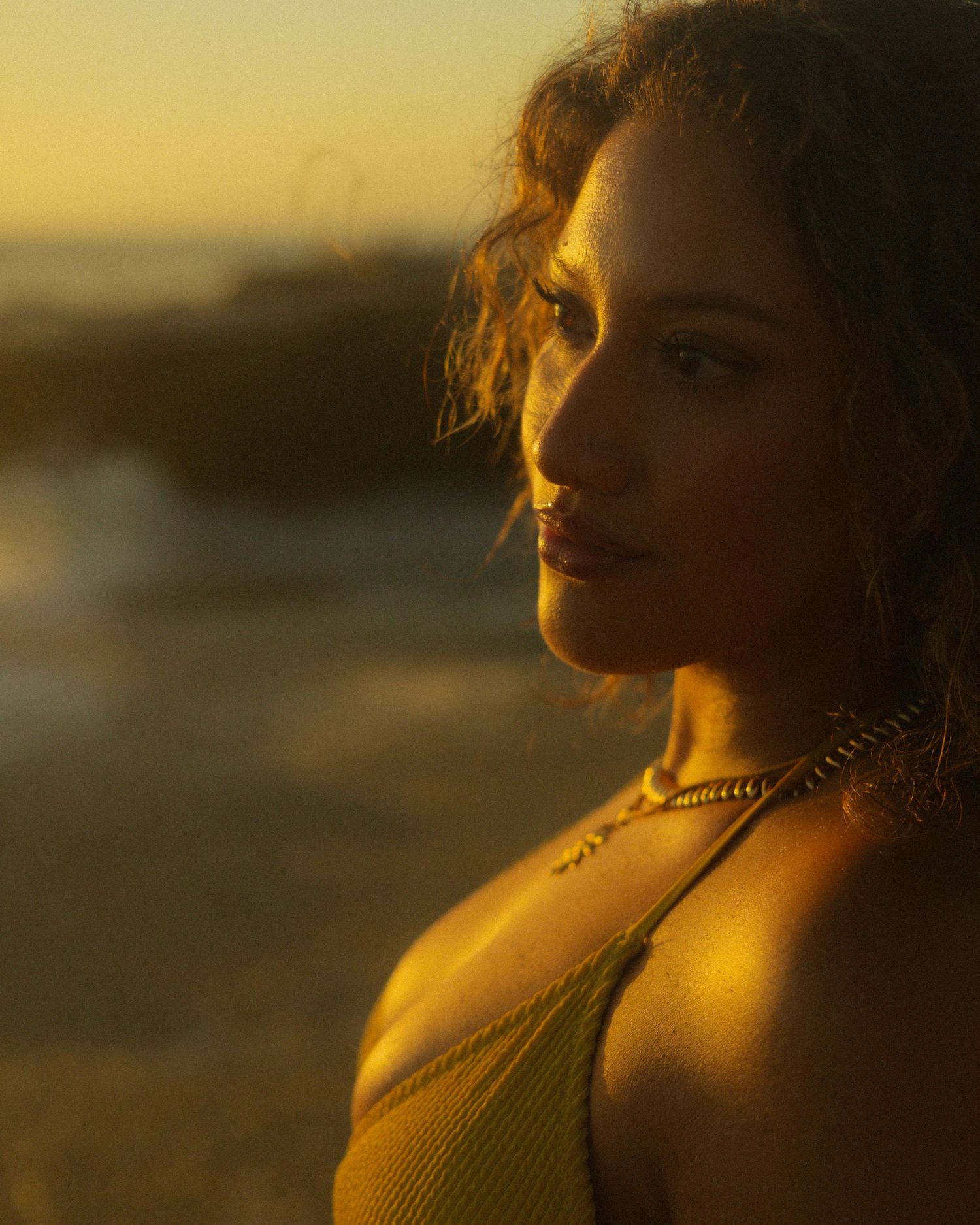 A silhouette of a person bathed in warm golden sunlight during sunset at the beach.