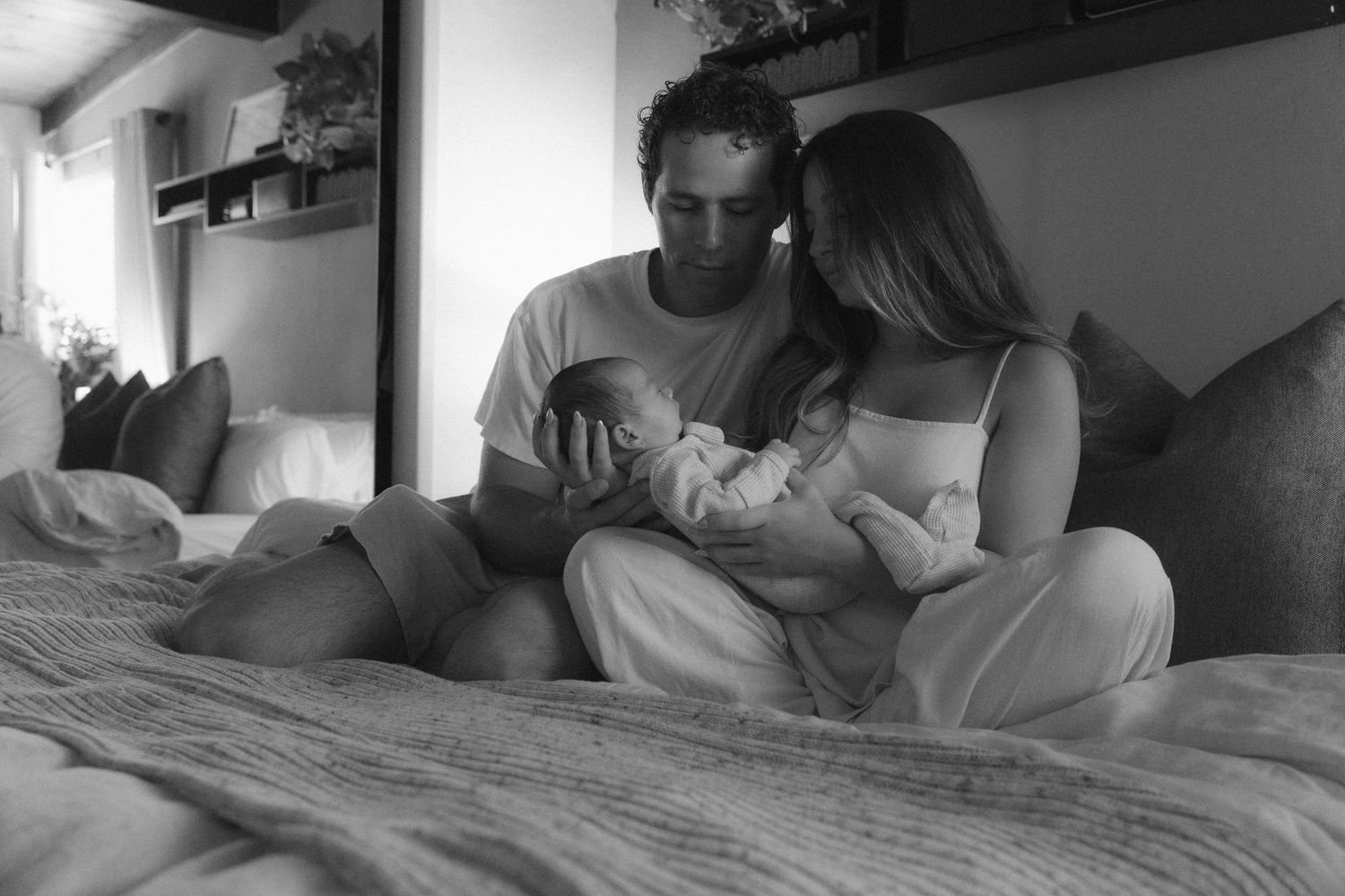 A series of black and white photographs showing intimate moments between two people relaxing on a bed.