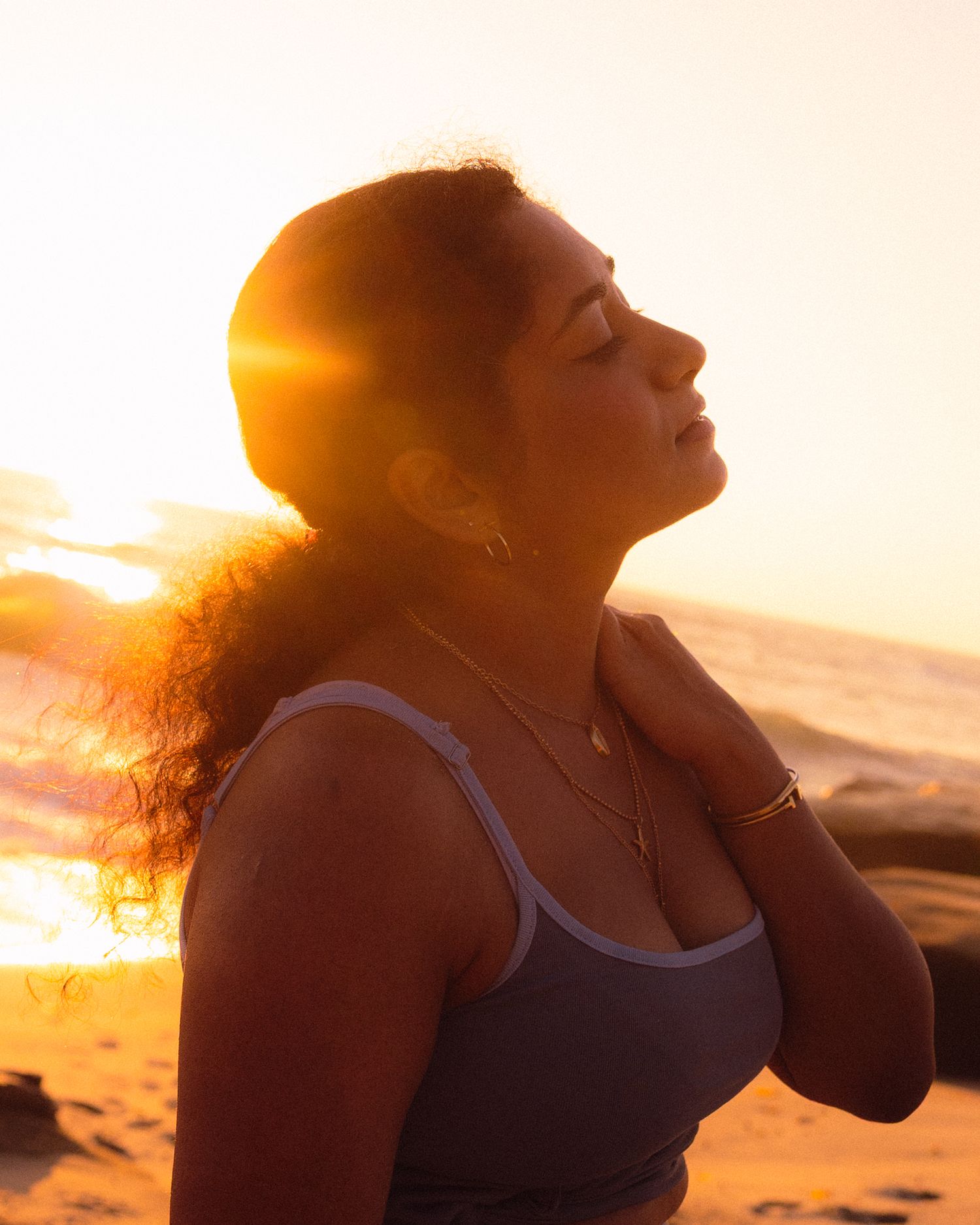 Athletic woman stretches outdoors against a vibrant sunset sky during her workout routine.