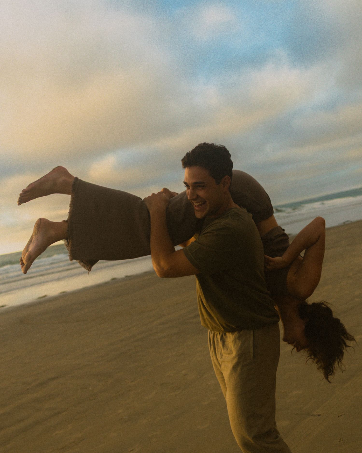 A sequence of silhouetted figures performing martial arts moves on a beach at sunset against a cloudy sky.
