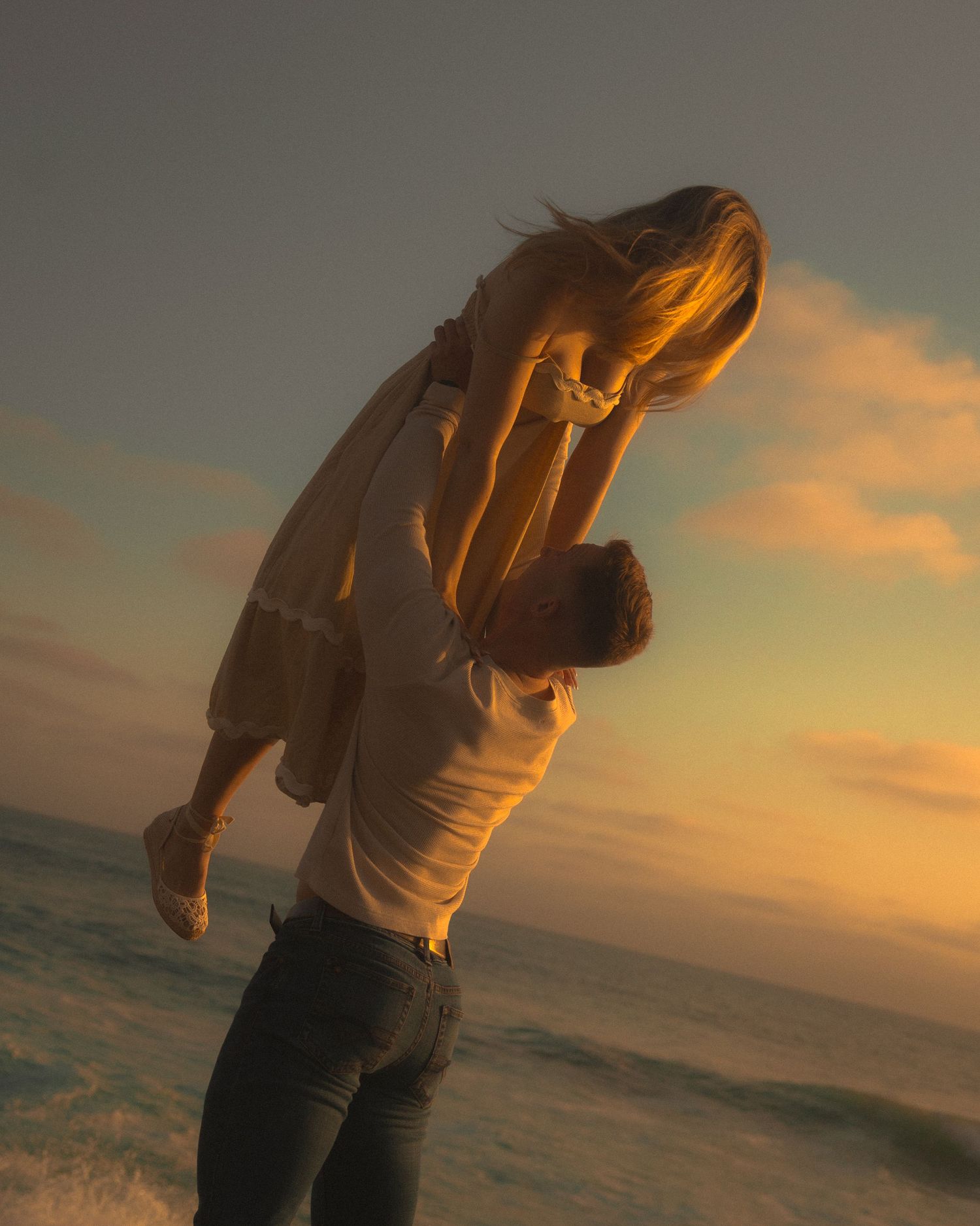 Silhouette of a couple embracing on a beach at sunset with golden light illuminating their romantic moment.