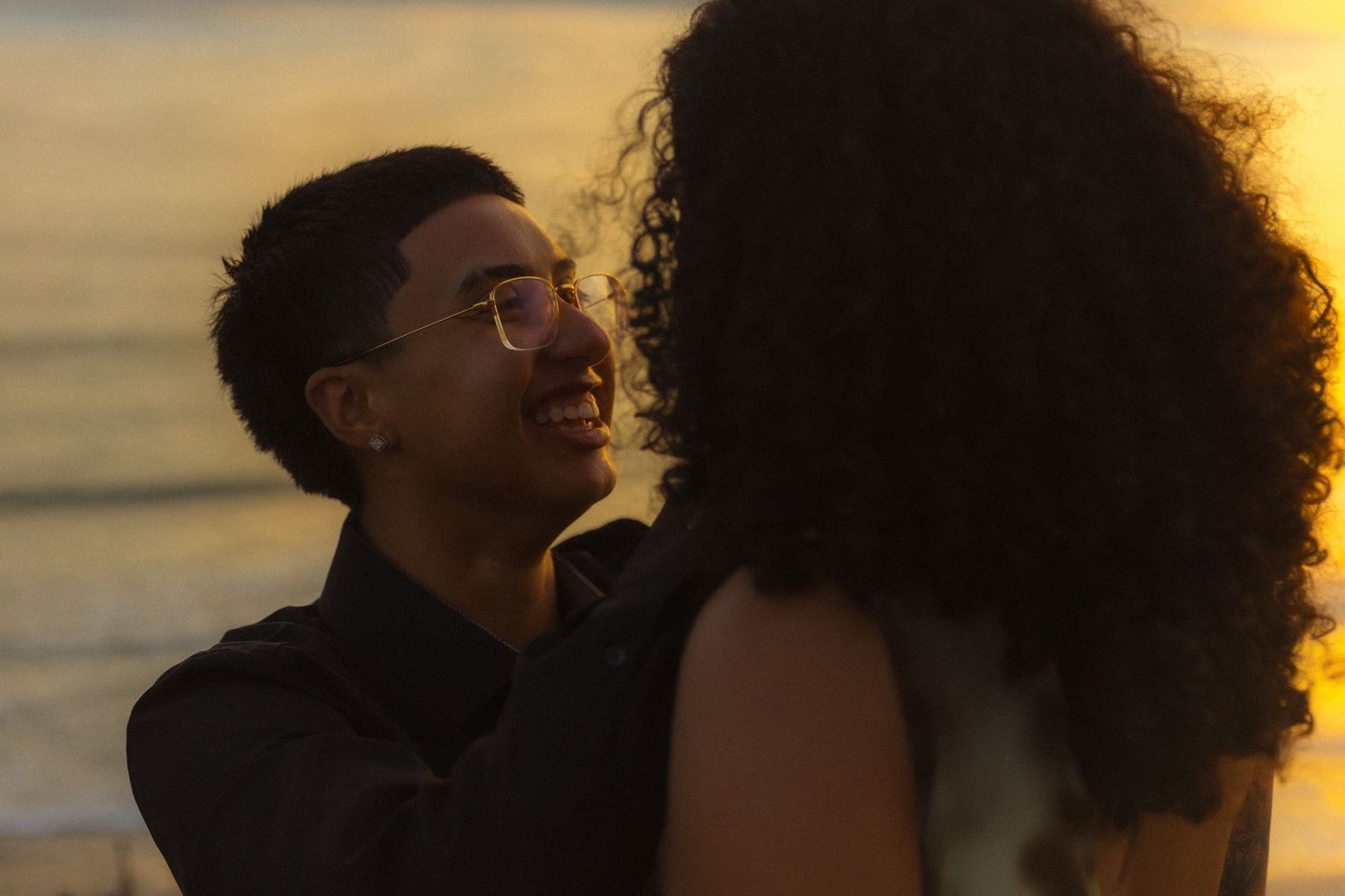 Silhouettes of people against a glowing sunset sky with curly hair illuminated by warm light.