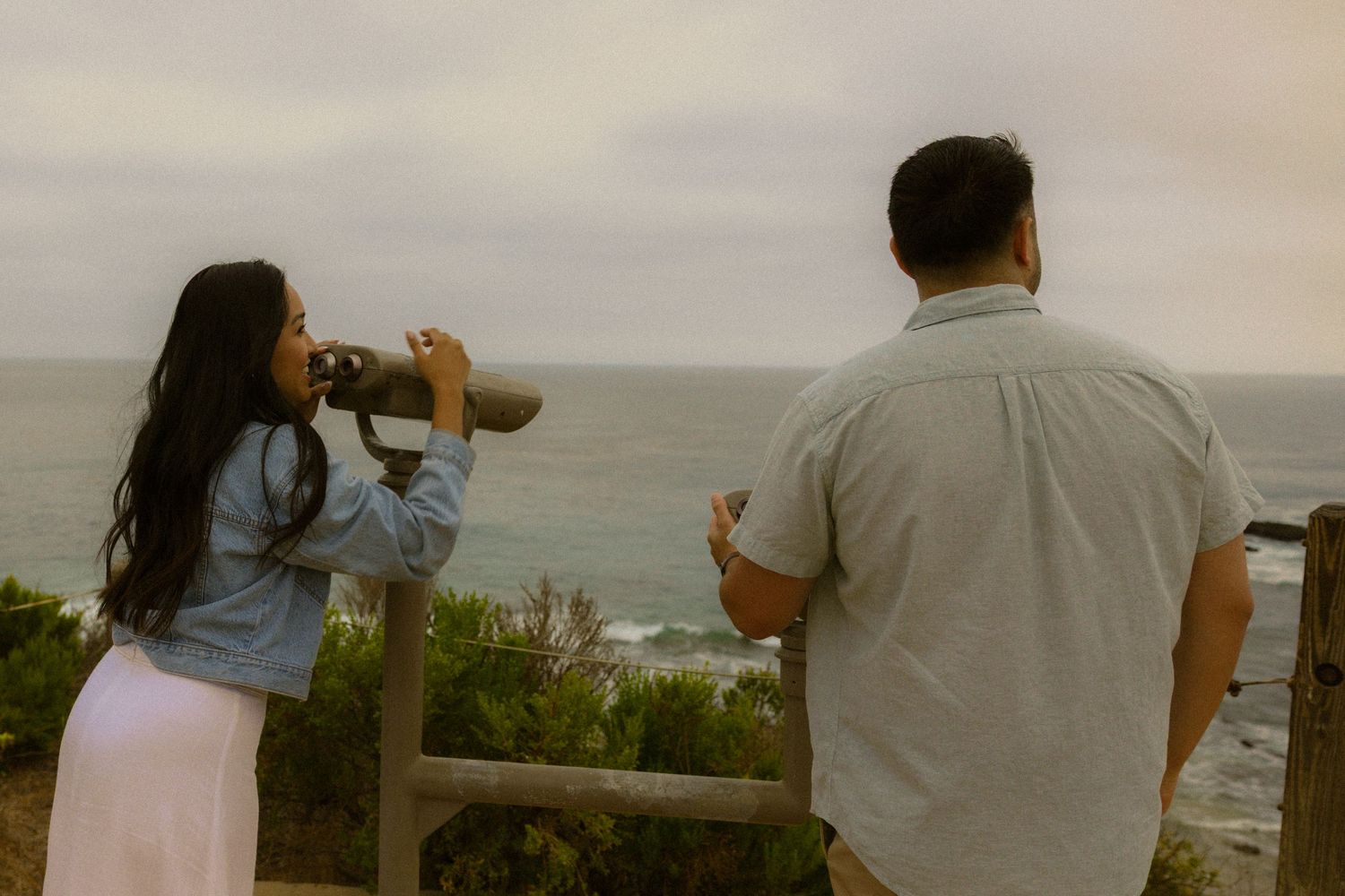 Six connected photos show a couple sharing romantic moments on a beach overlook with ocean views in the background.