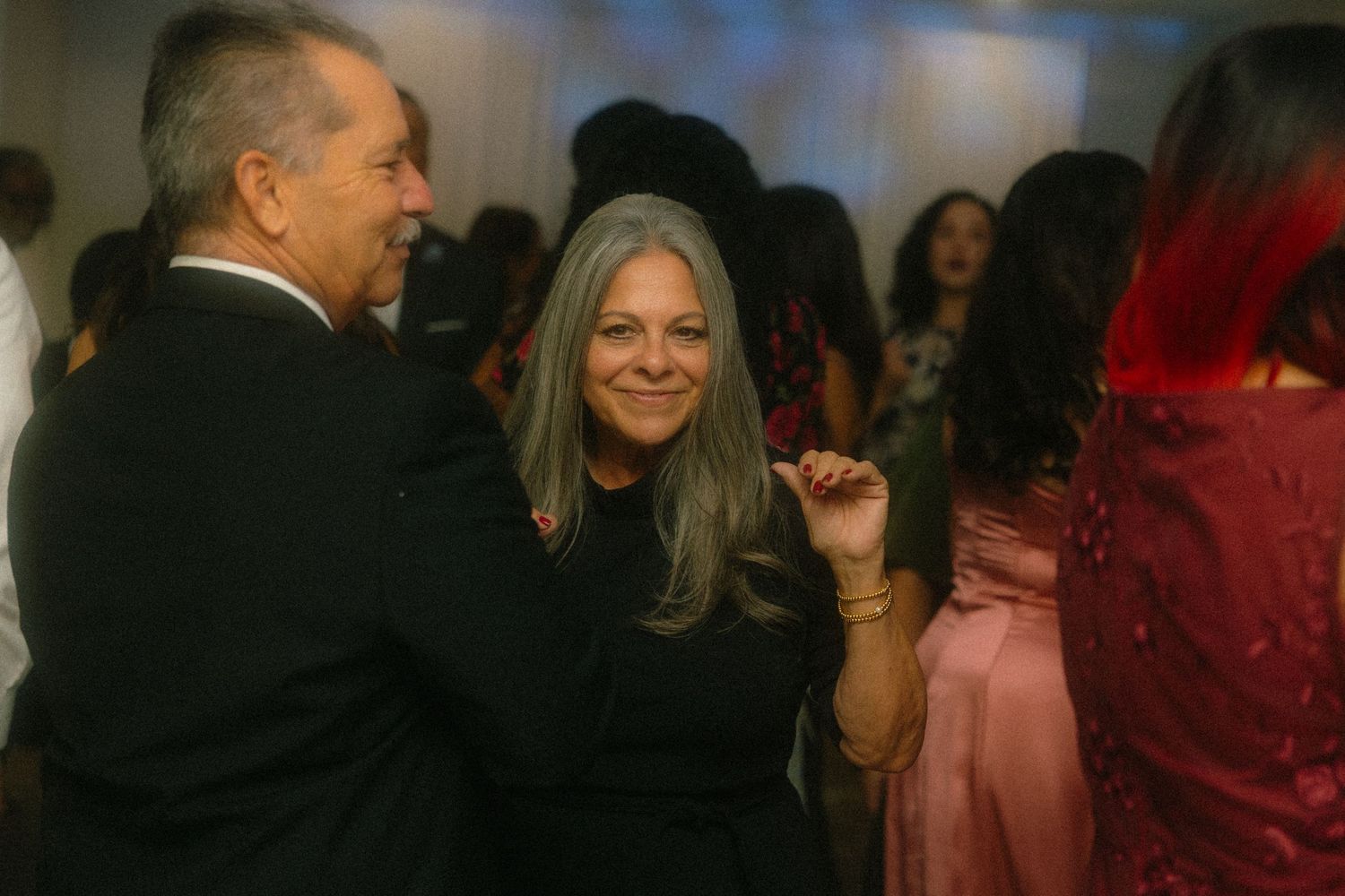 Wedding reception guests mingling and socializing in an elegantly lit indoor venue.