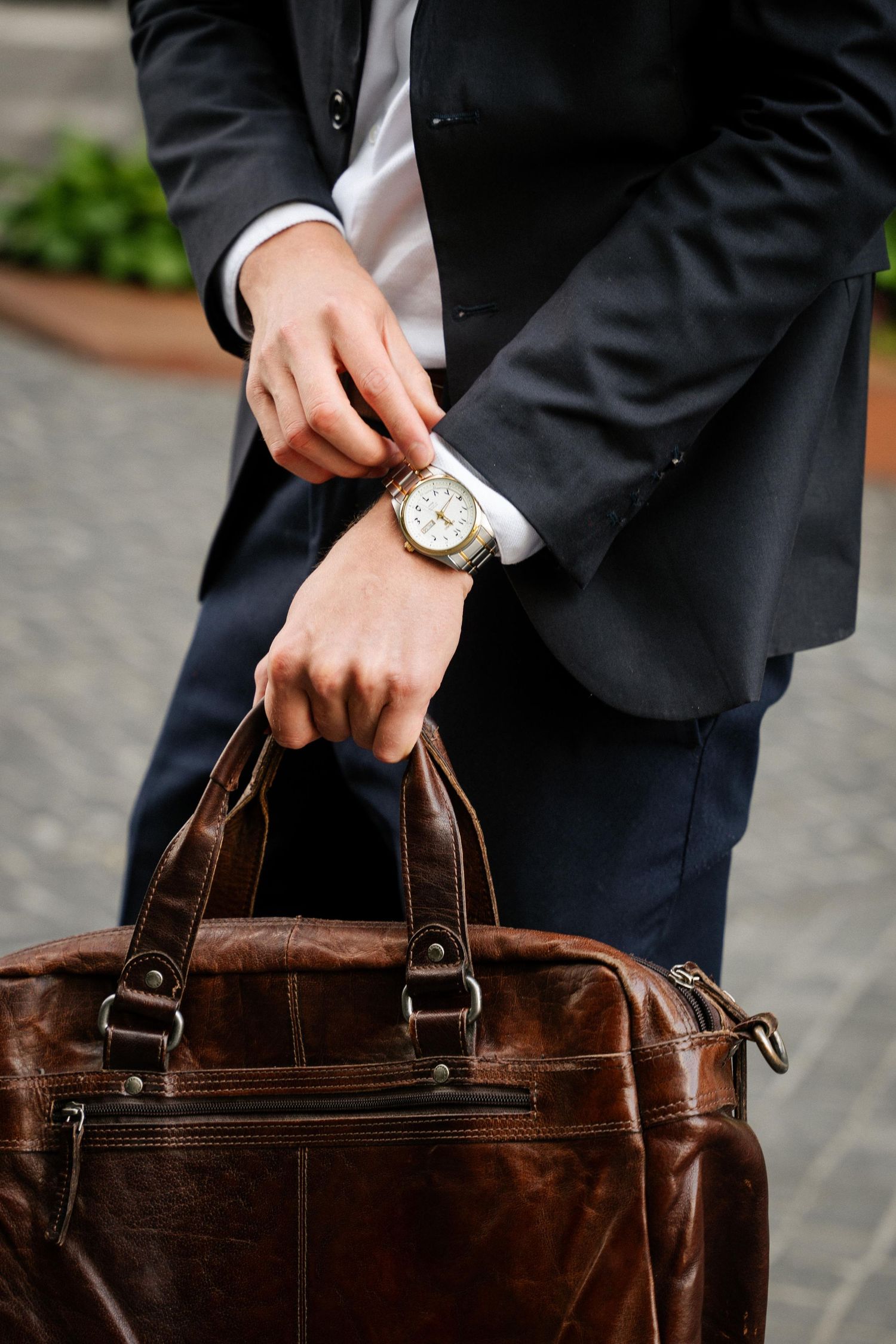 Professional holding a brown leather briefcase shown from different angles with focus on watch and handle details.
