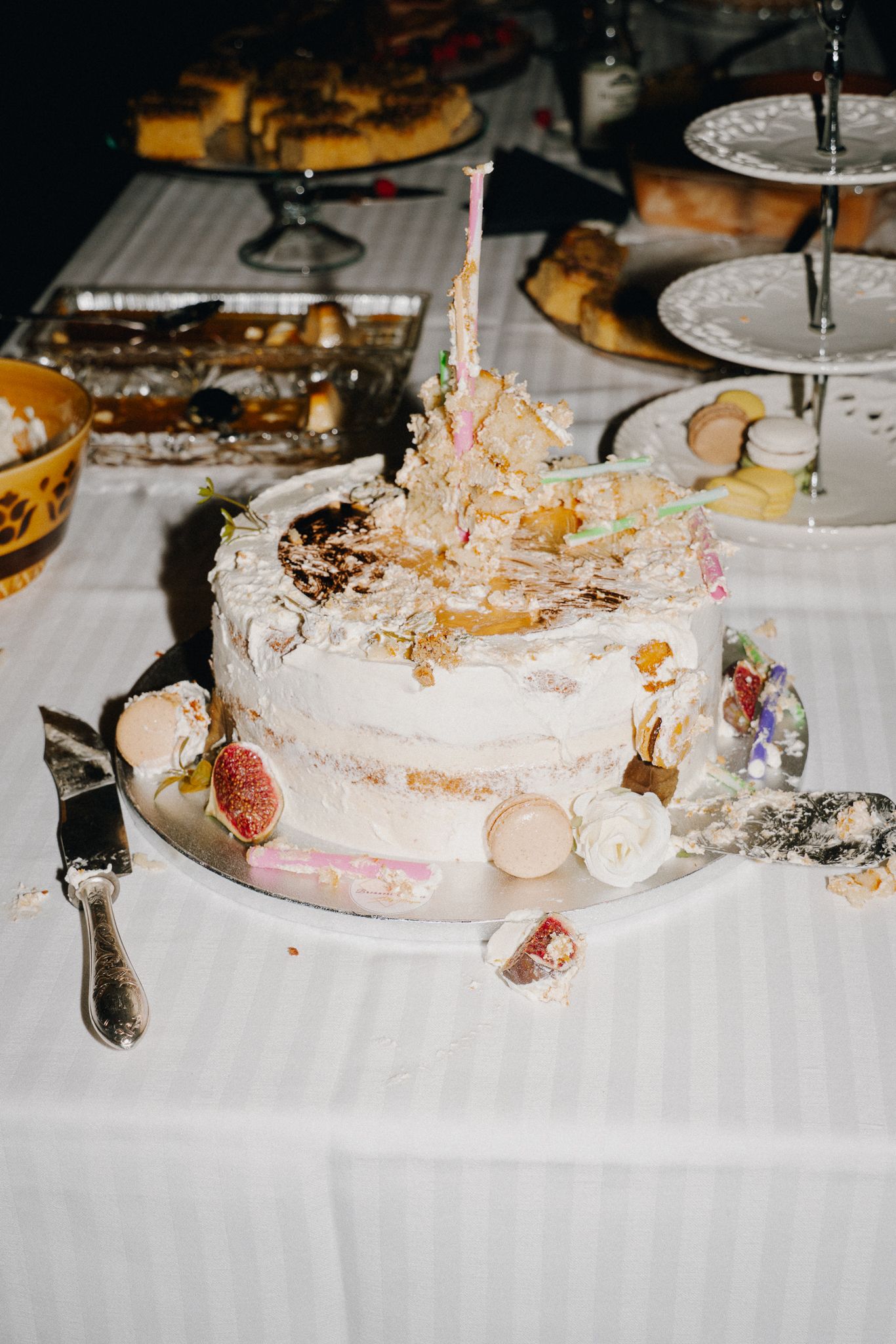A series of partially eaten white wedding cakes on a table with scattered crumbs and decorative details.