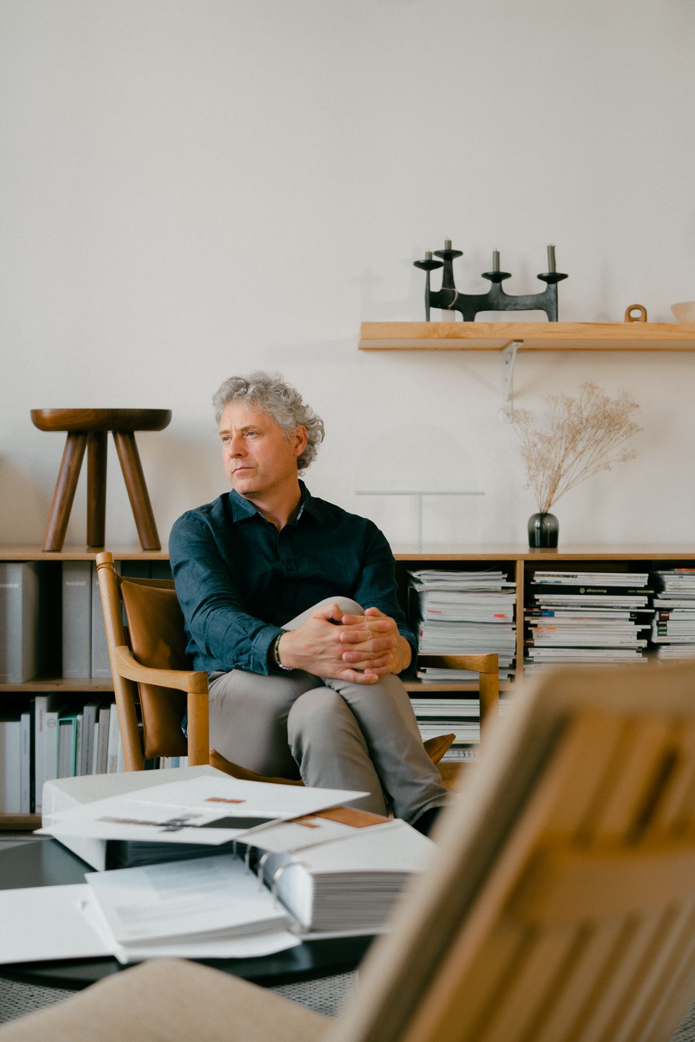 Professional sitting thoughtfully in modern office space with minimalist decor and natural lighting.