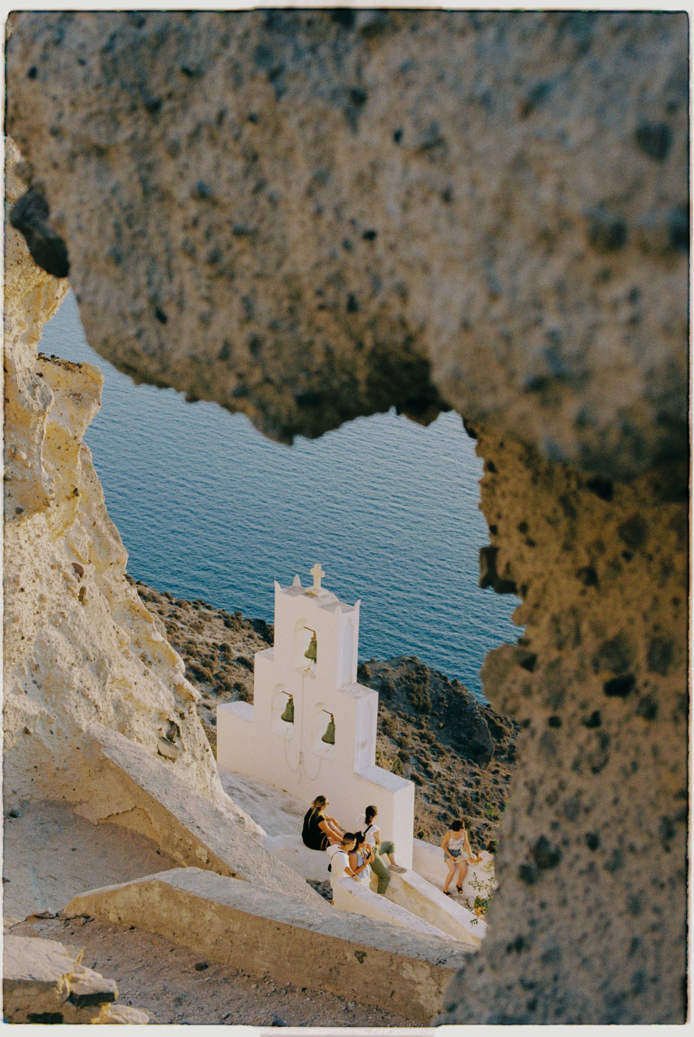 White Mediterranean church perched on cliffs overlooking deep blue waters of Santorini, Greece.