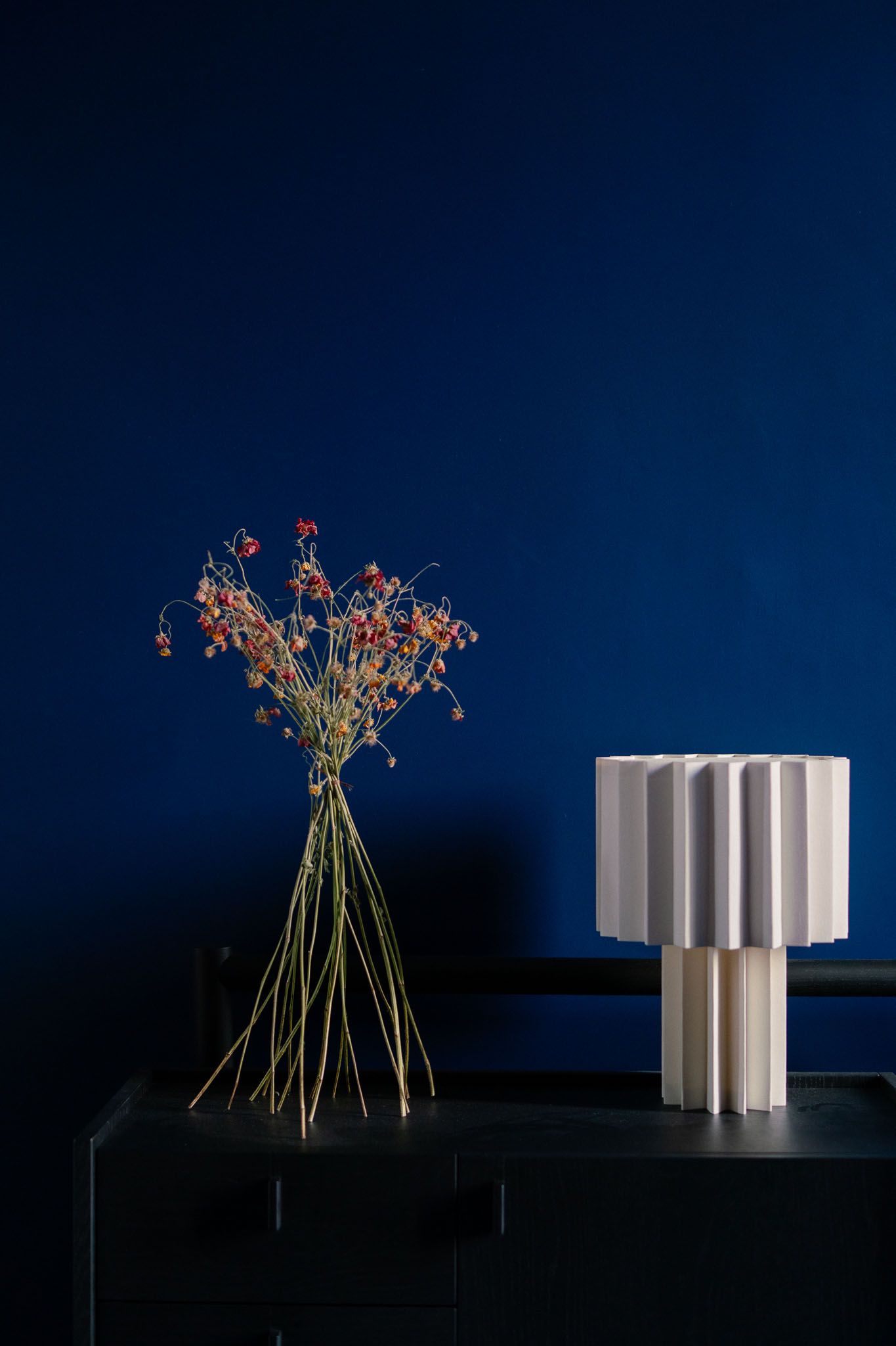 White architectural structure with delicate red flowers against a deep blue night sky background.