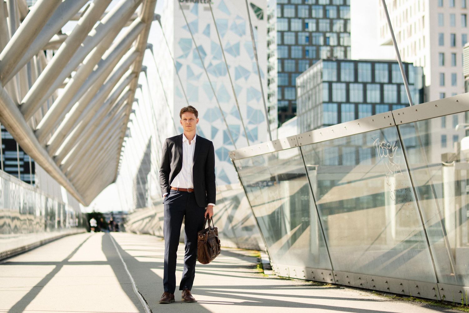 Professional in a business suit stands confidently on modern architectural steps with glass and steel elements in background.