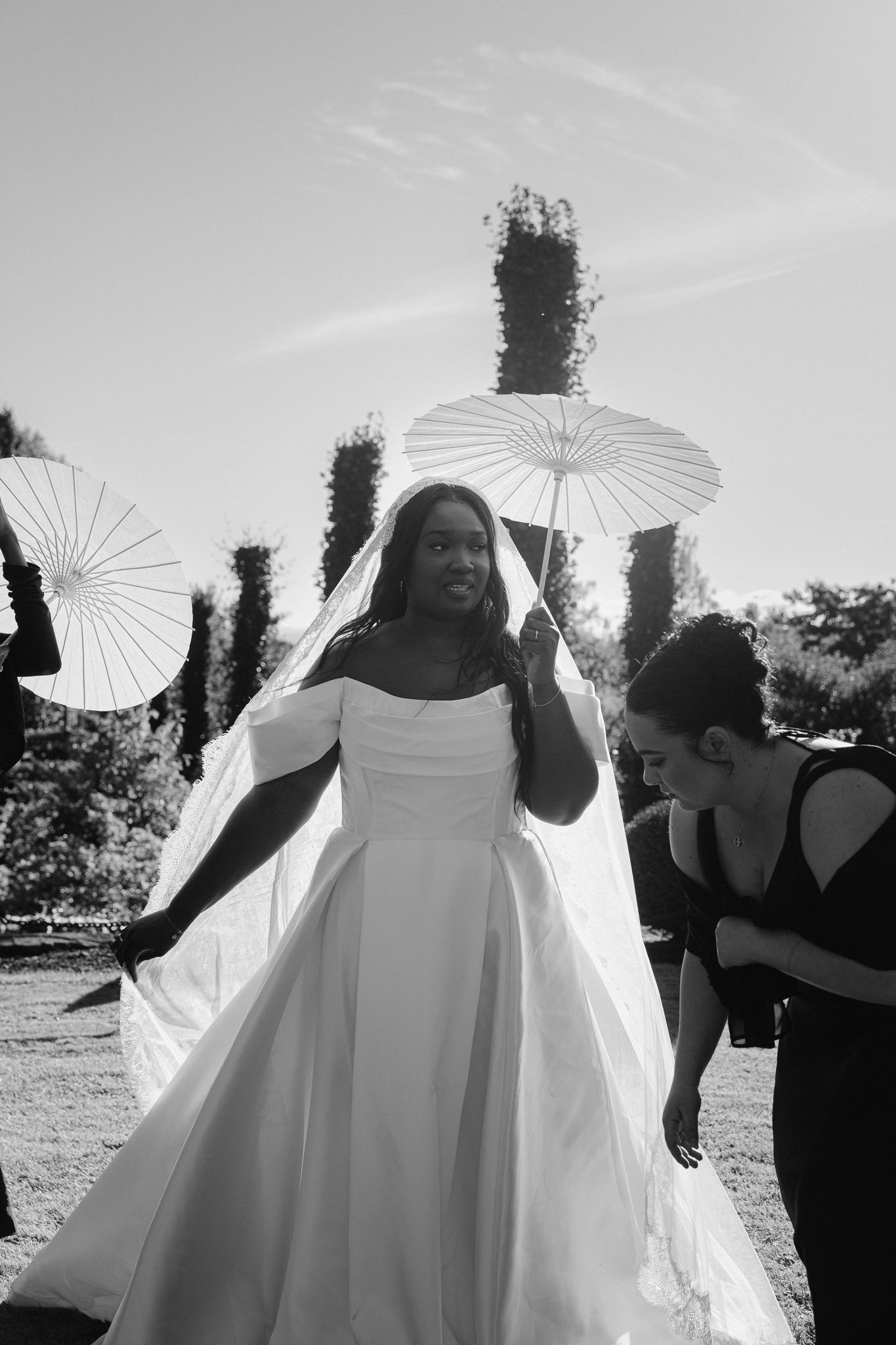 A sequence of black and white wedding photos showing a bride with a parasol in an outdoor setting.