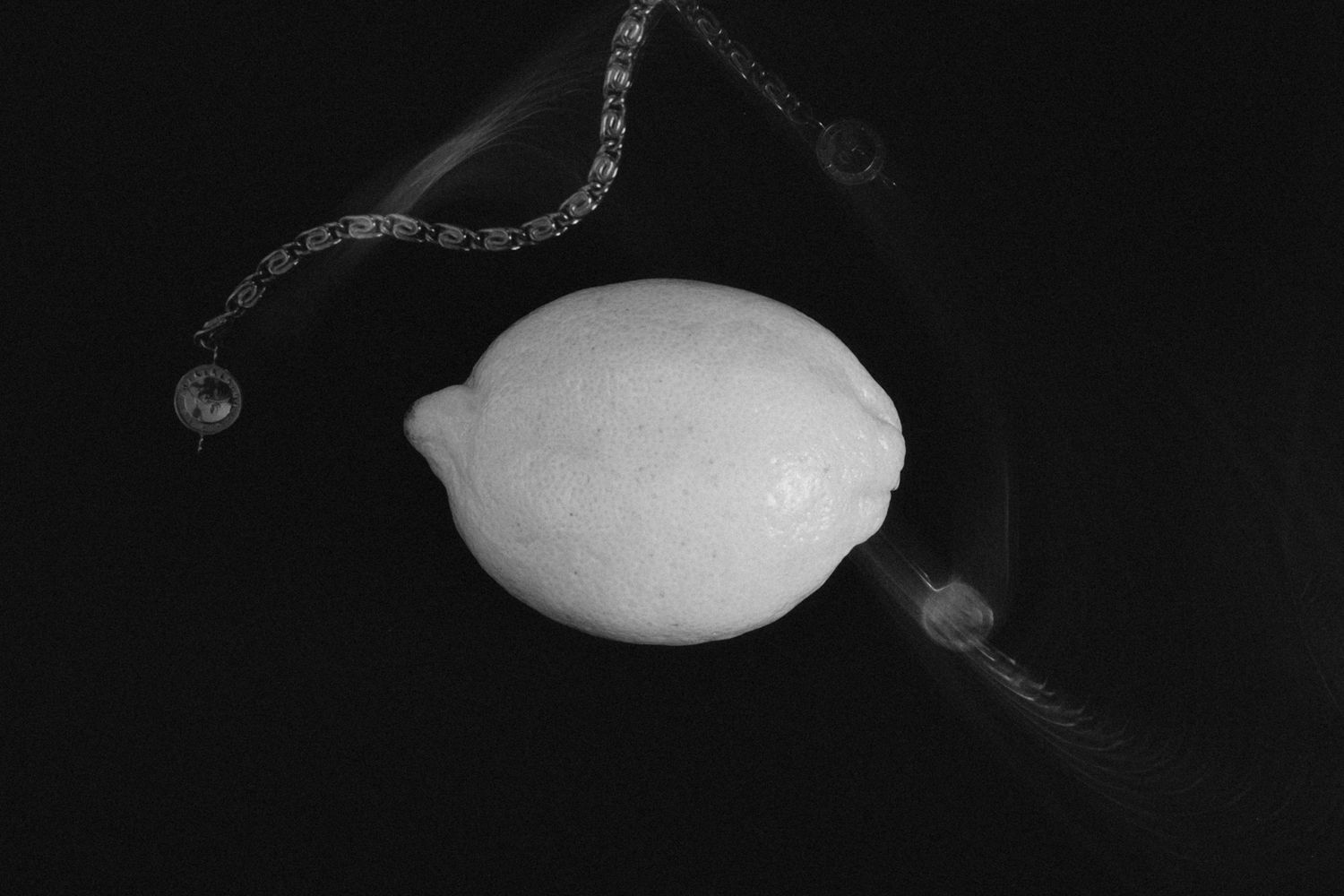 A black-and-white still life featuring a lemon and a Louis Sabel bracelet, captured with a slow shutter to convey motion in the bracelet.