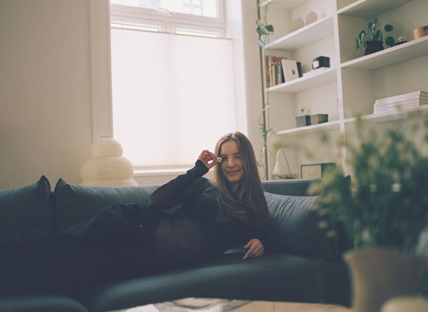 A sequence of four photos shows someone lying comfortably on a couch in a bright, sunlit room with shelving.