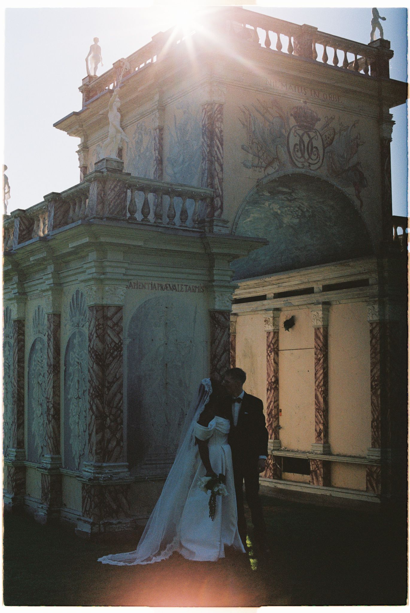 A sequence of outdoor wedding photos showing figures in white against an ornate classical building facade at sunset.