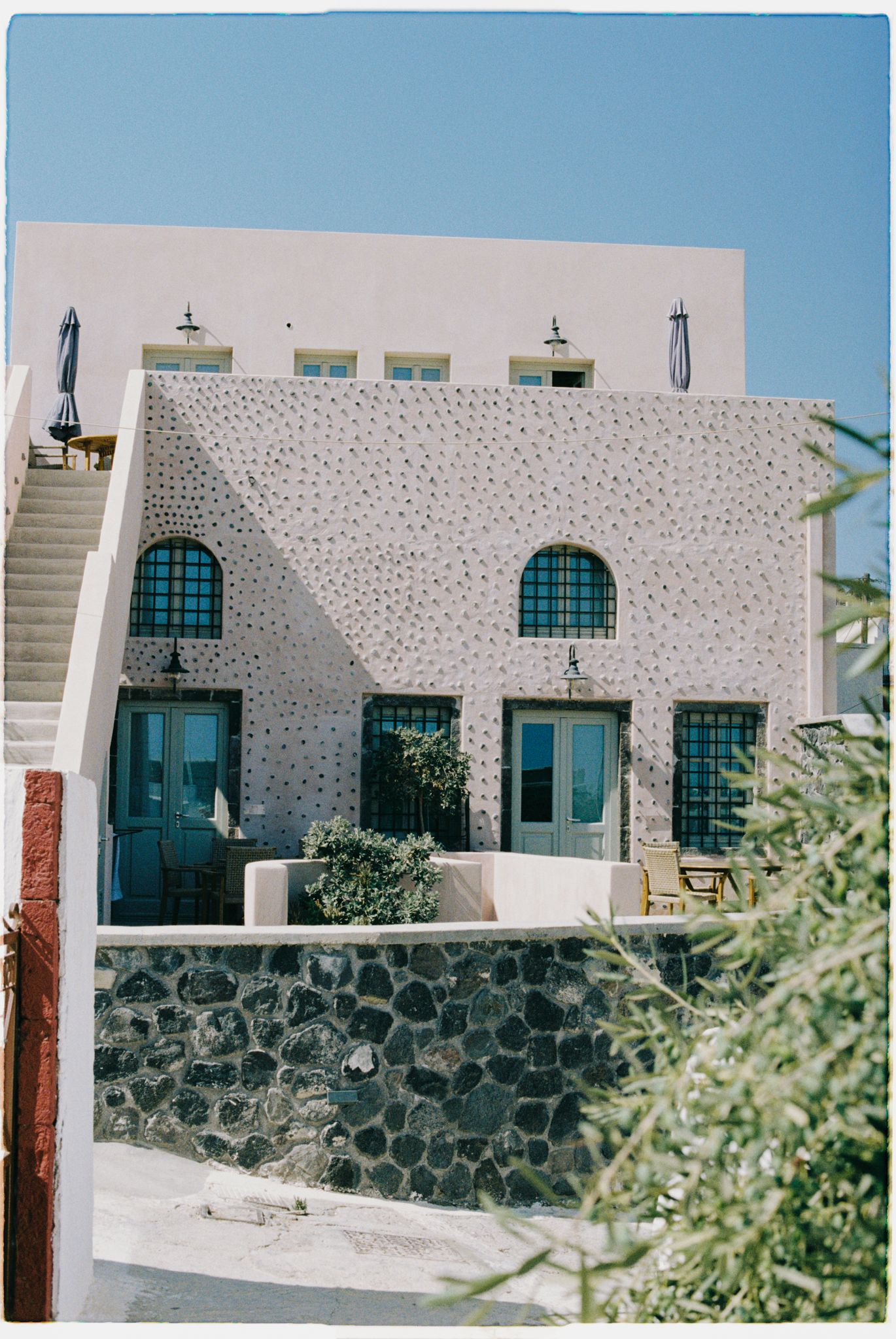 A stone building with turquoise windows and doors features traditional Arabian architectural style against a clear sky.