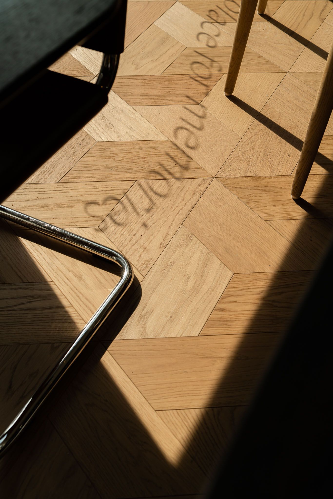Dramatic shadows cast across a wooden parquet floor create geometric patterns in a sequence of architectural photographs.