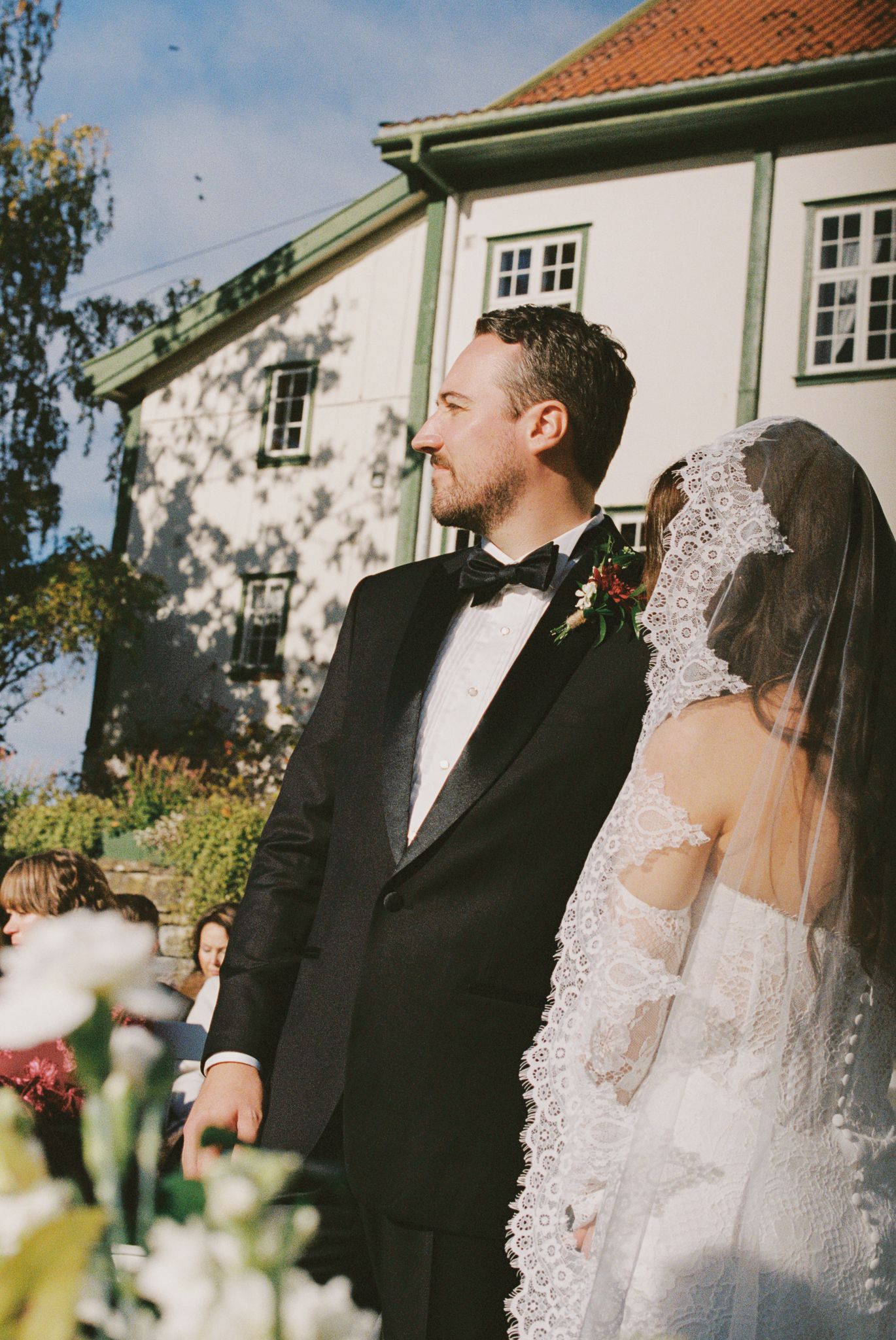A series of wedding photos showing a couple in traditional formal attire sharing joyful moments outside a white building.