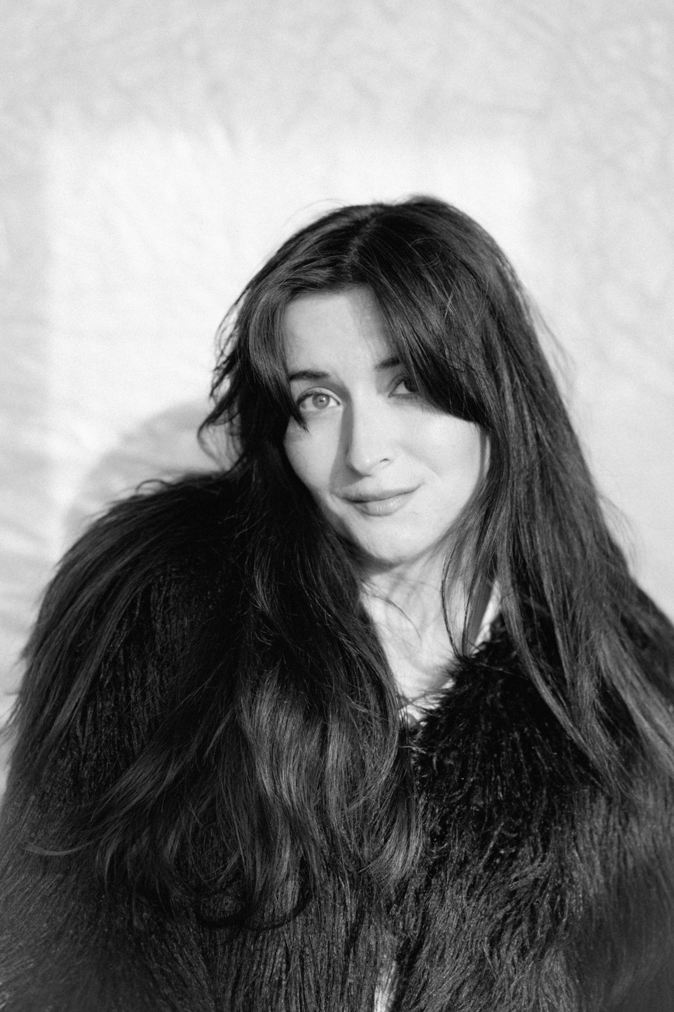 A  black and white portrait showing a woman with long dark hair against a light background.