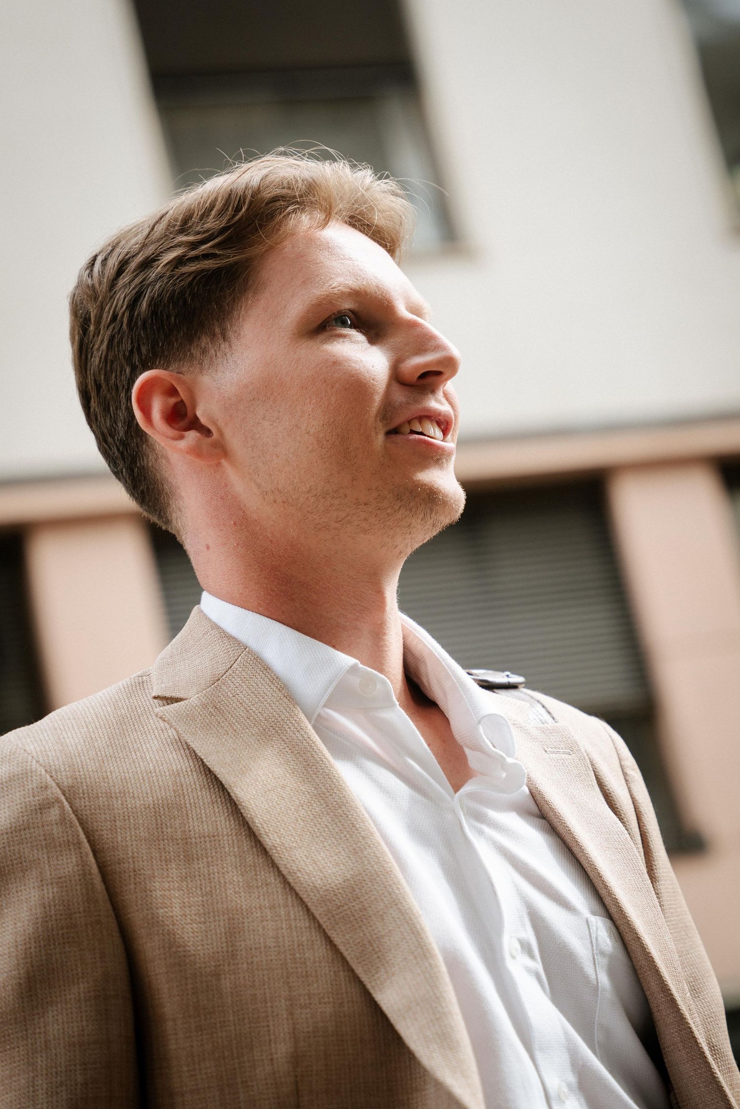 Side profile portrait showing someone wearing a light colored suit and white shirt looking upward.