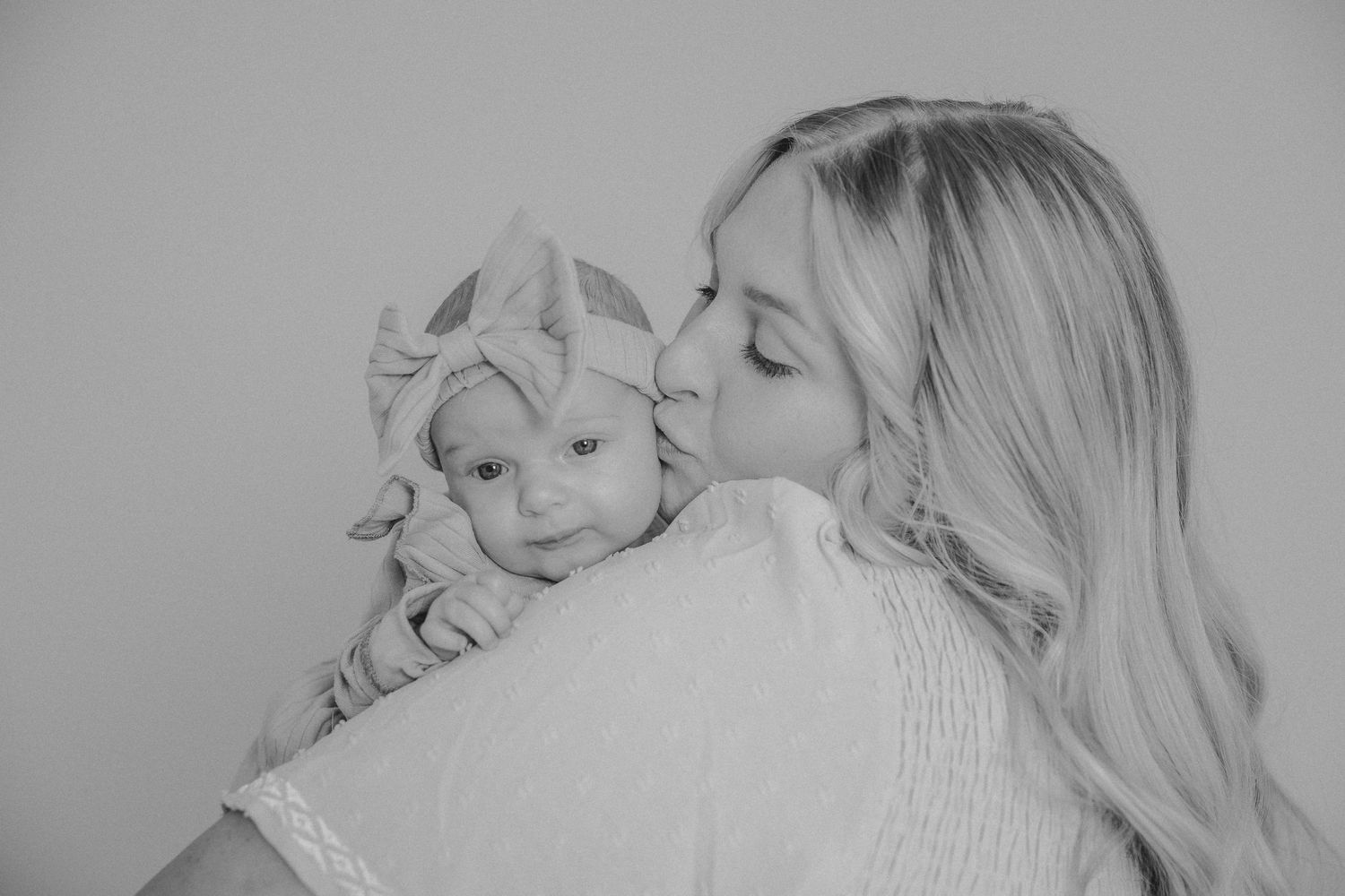 Black and white intimate portrait showing tender moment between parent and infant.