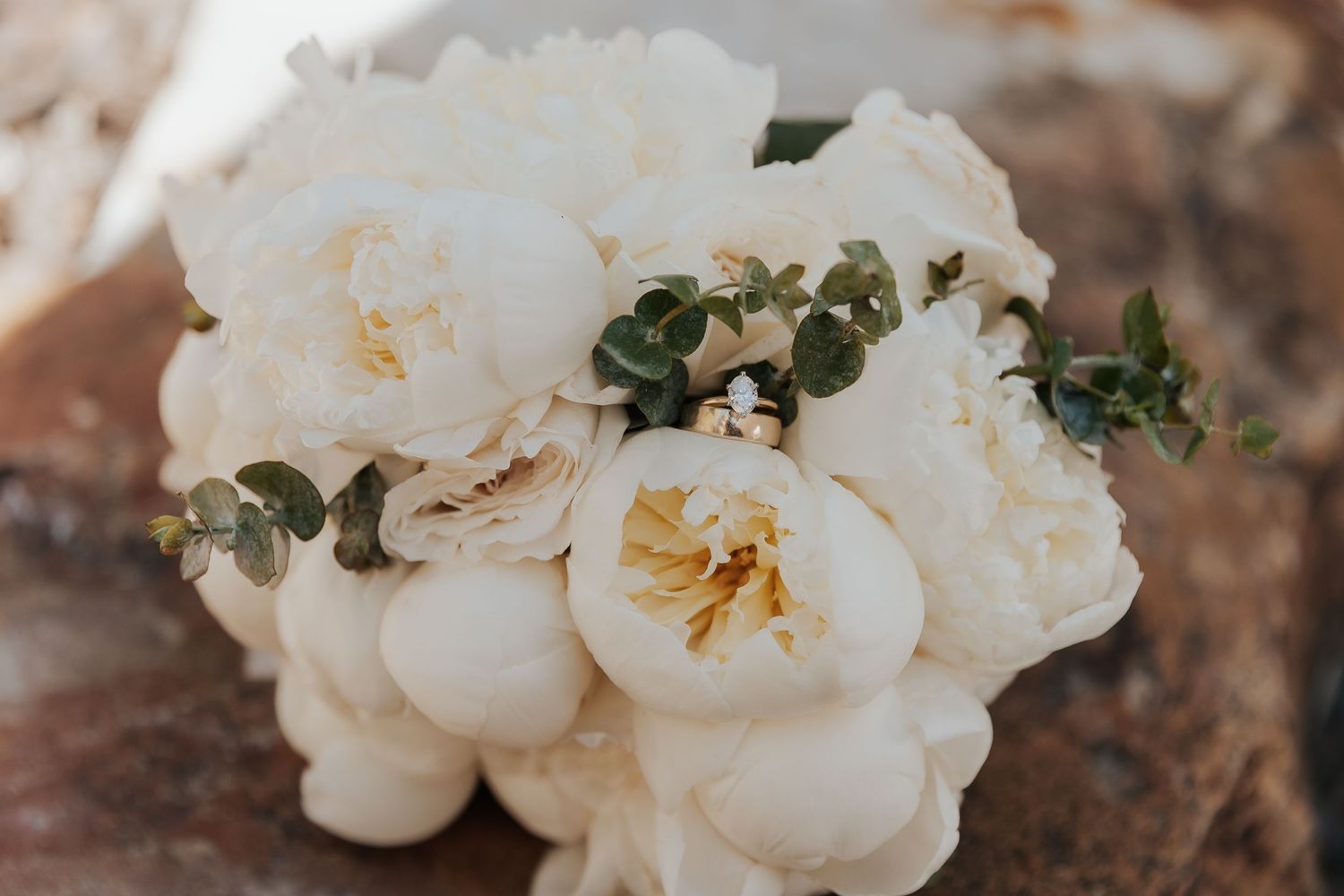 Delicate white peonies and green eucalyptus leaves form an elegant wedding bouquet arrangement.