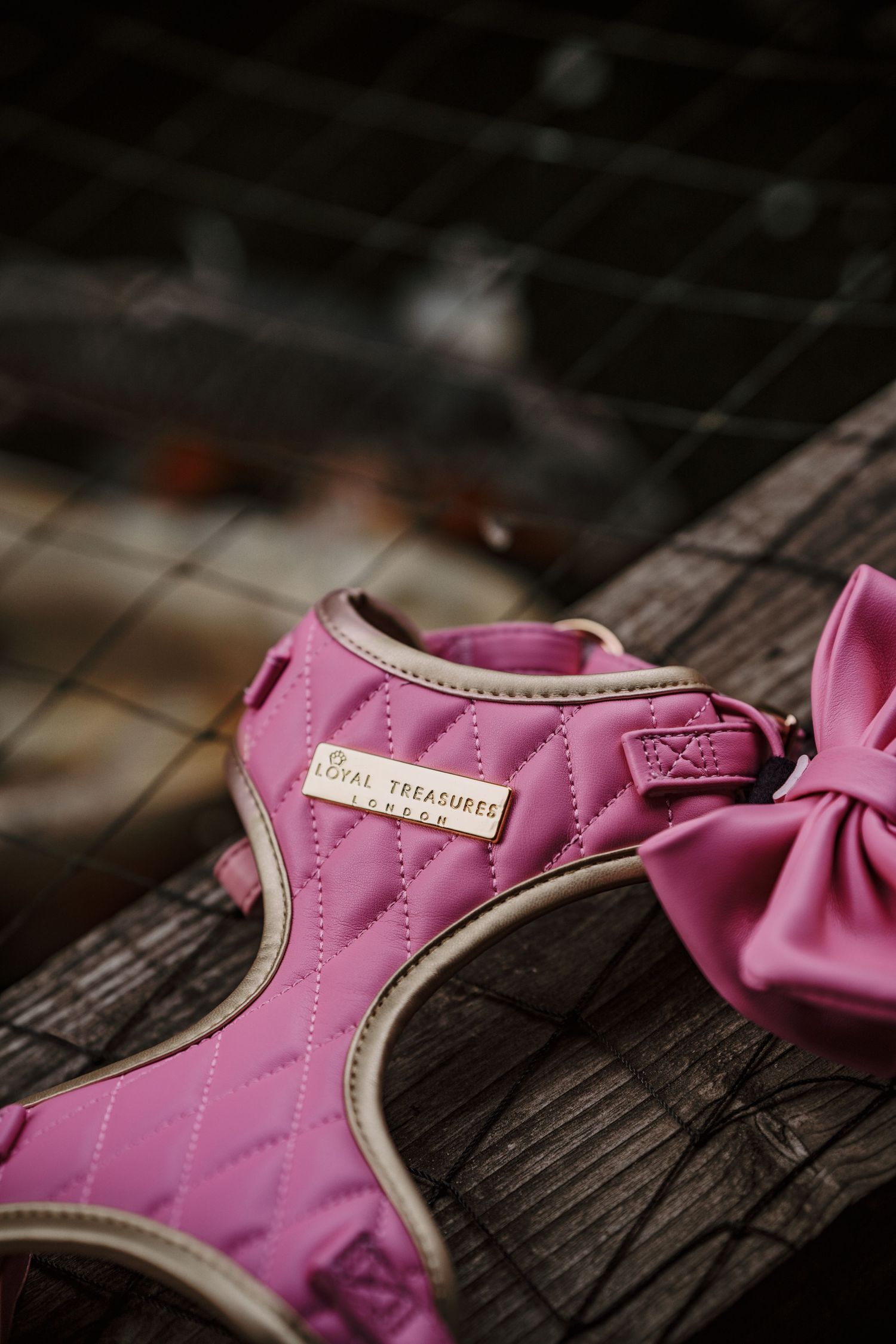 Pink quilted dog harness with bow by Royal Treasures, displayed on wooden surface.
