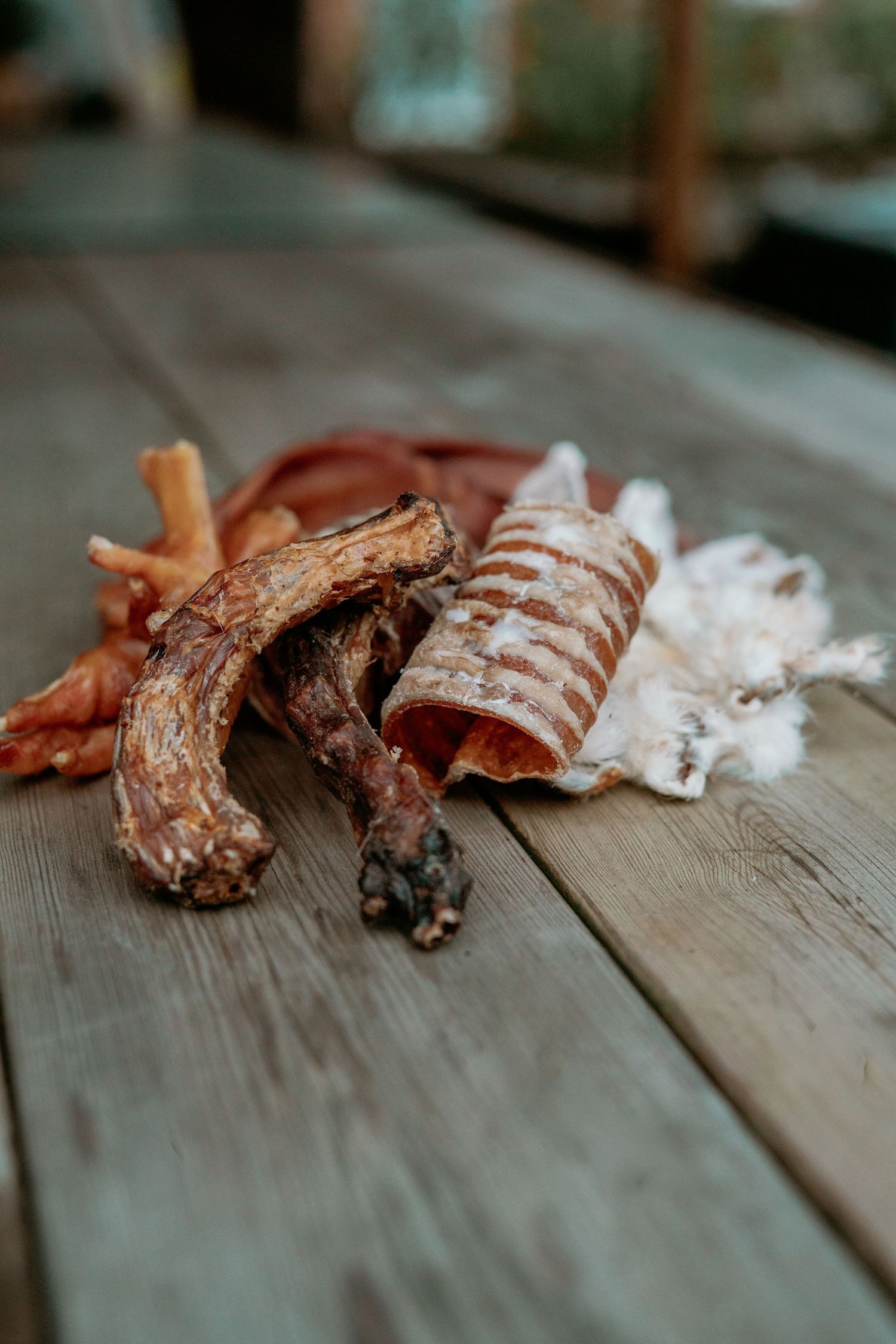Assorted dried meat dog treats displayed on a rustic wooden surface, including chews and bones.