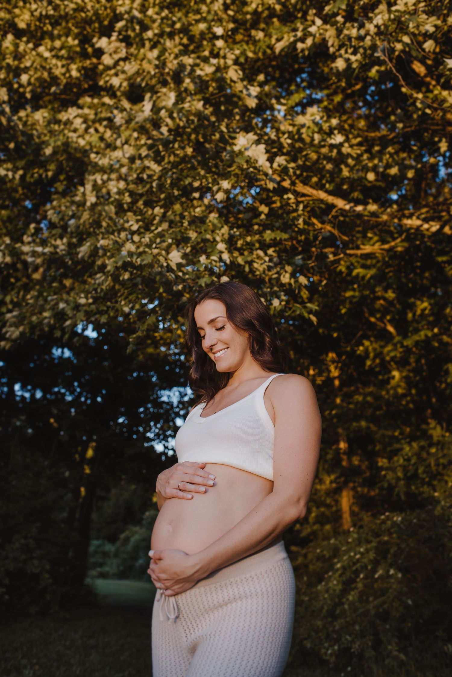 Maternity photos capturing golden hour light through autumn trees.