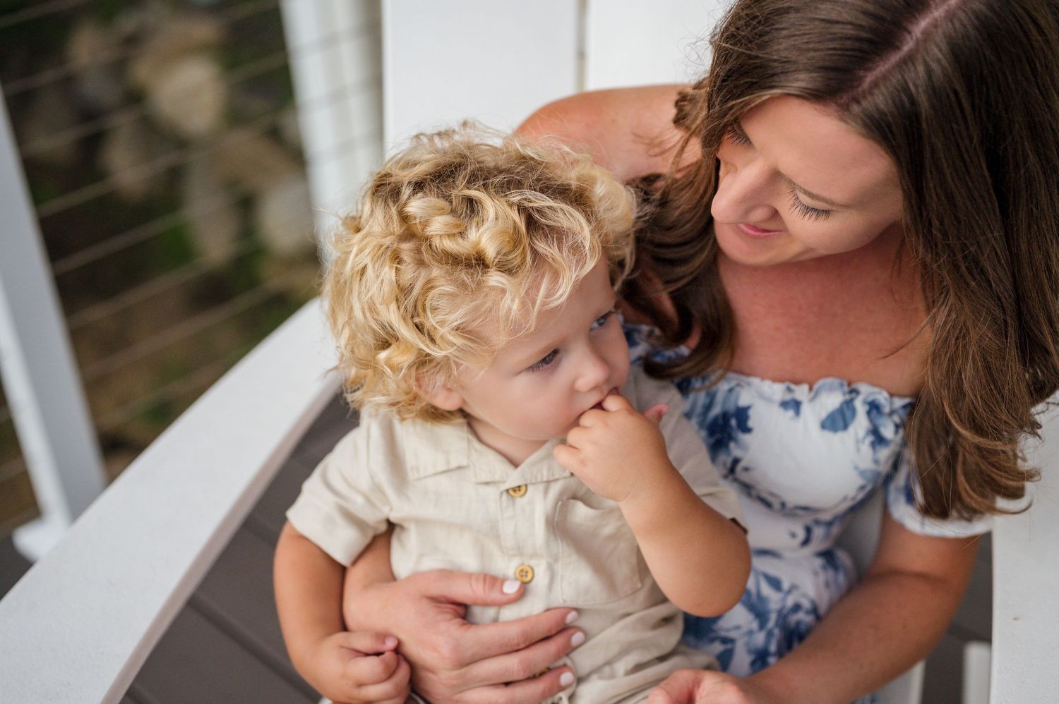 A tender moment captured outdoors on a white porch during a family photoshoot.