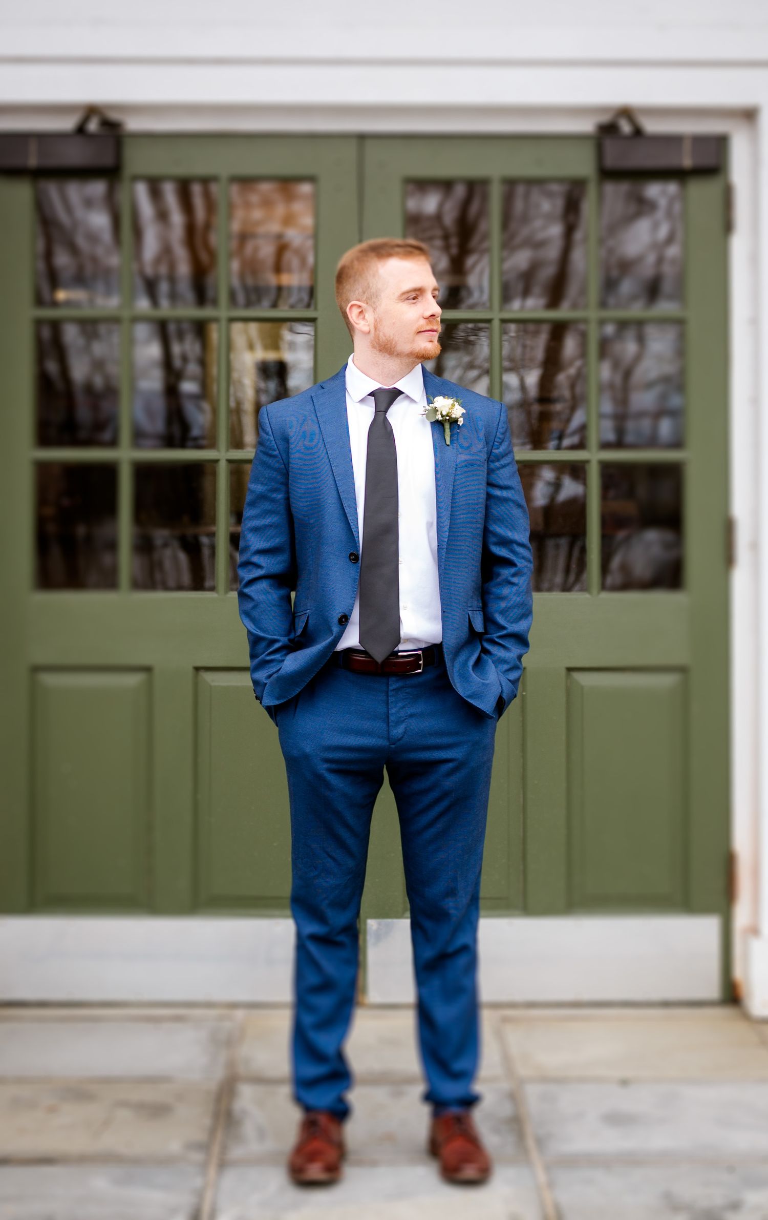 Navy blue suit against green doors of a classic building exterior.