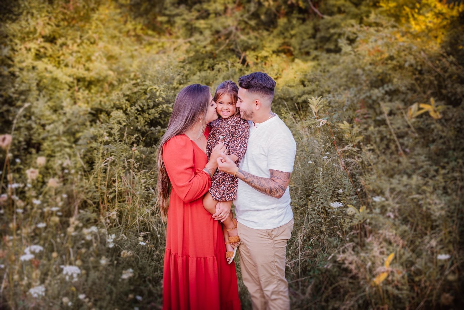 Family maternity photoshoot in a natural outdoor setting with golden light.