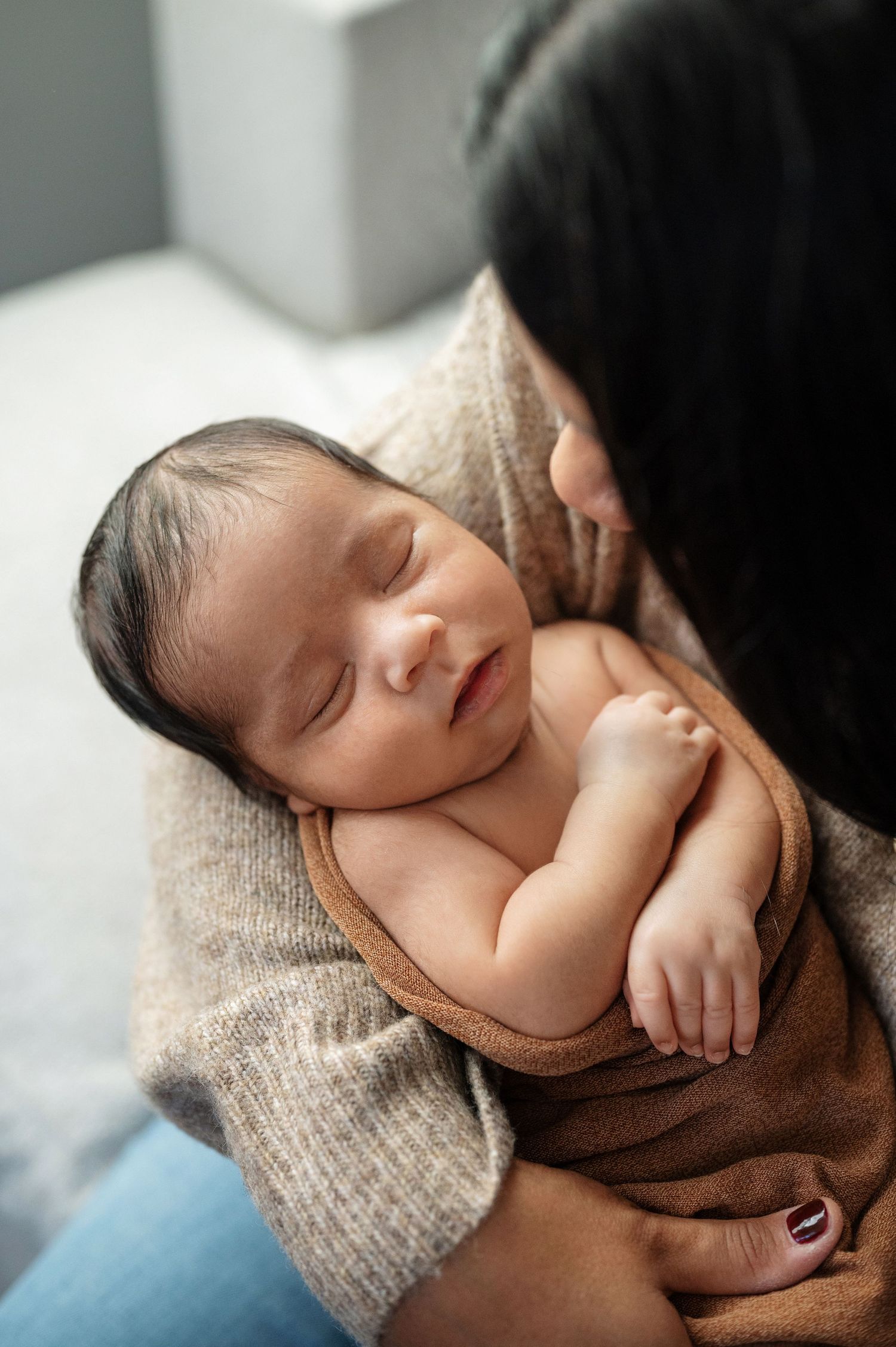 Peaceful sleeping newborn wrapped in cozy brown knit blanket.
