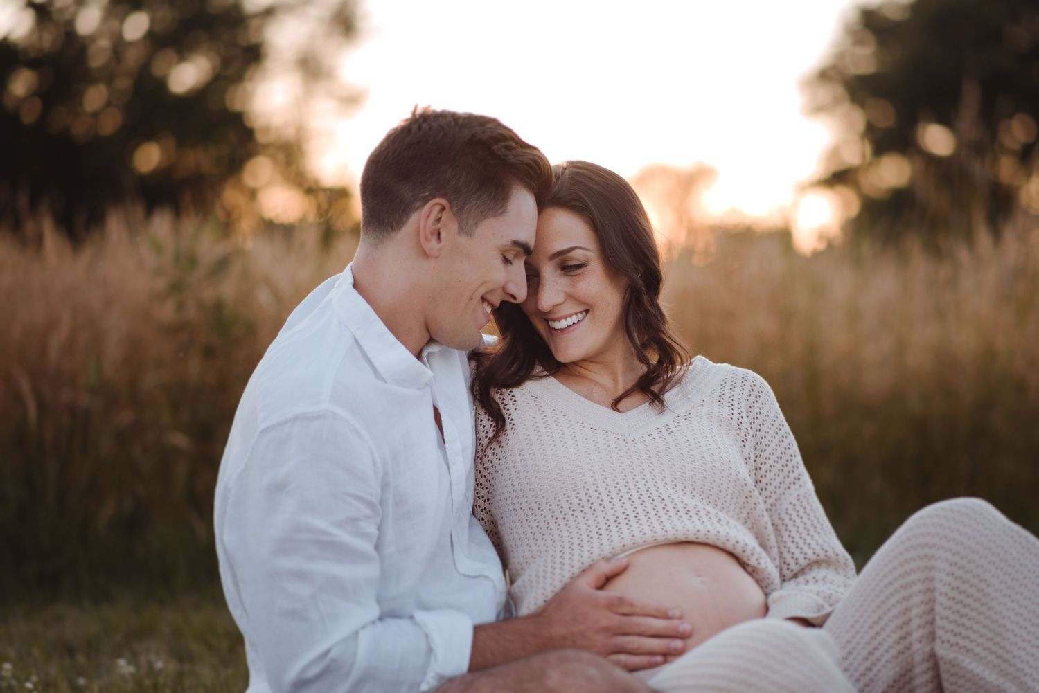 Intimate maternity session at sunset with couple sharing tender moments.