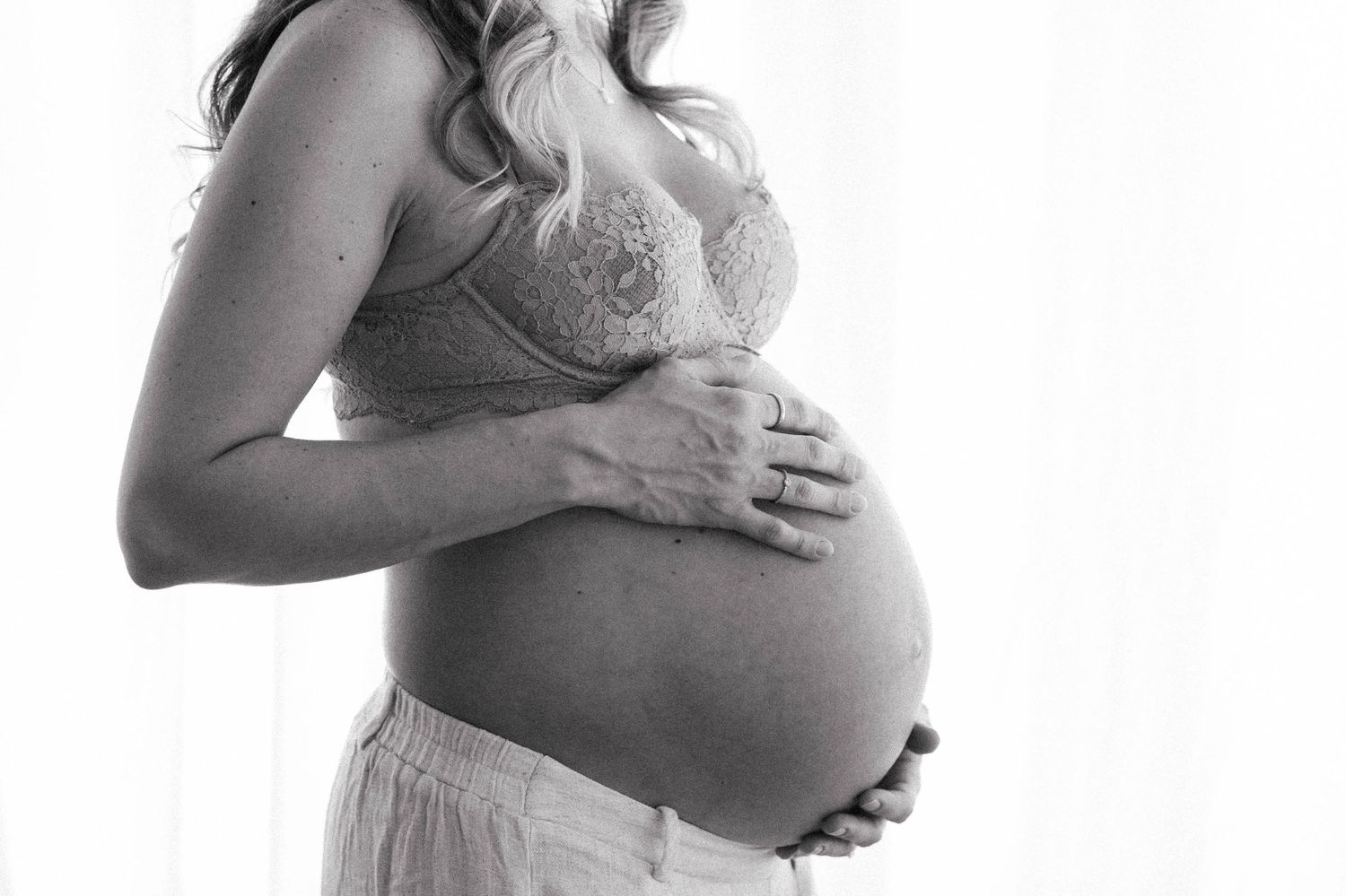 A series of black and white maternity photos showing pregnant women cradling their bellies in artistic poses.