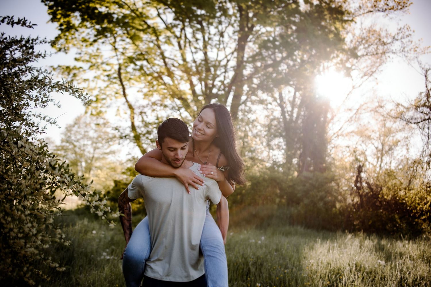 Couple embracing in golden sunlit field during sunset.