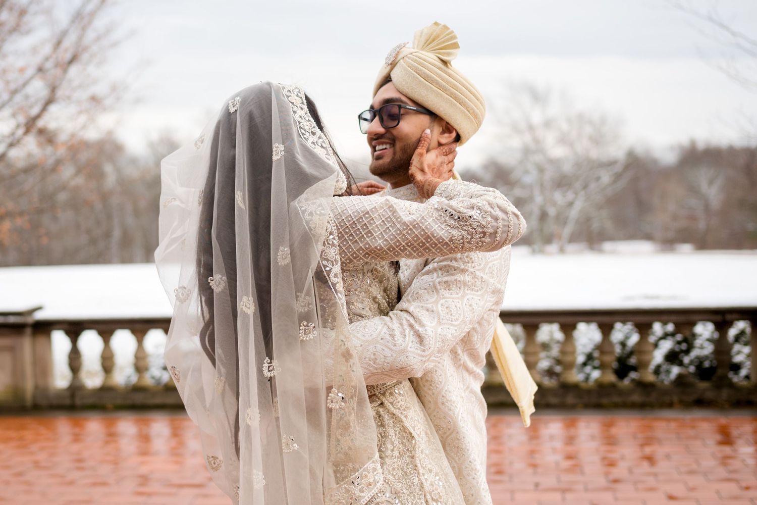 Winter wedding portraits with flowing veil and delicate lace details against snowy landscape.
