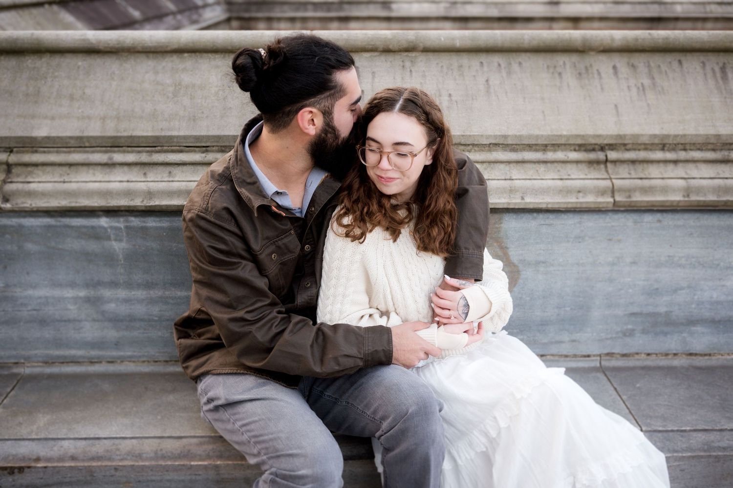 Couple sitting close together on stone steps of a historic building.