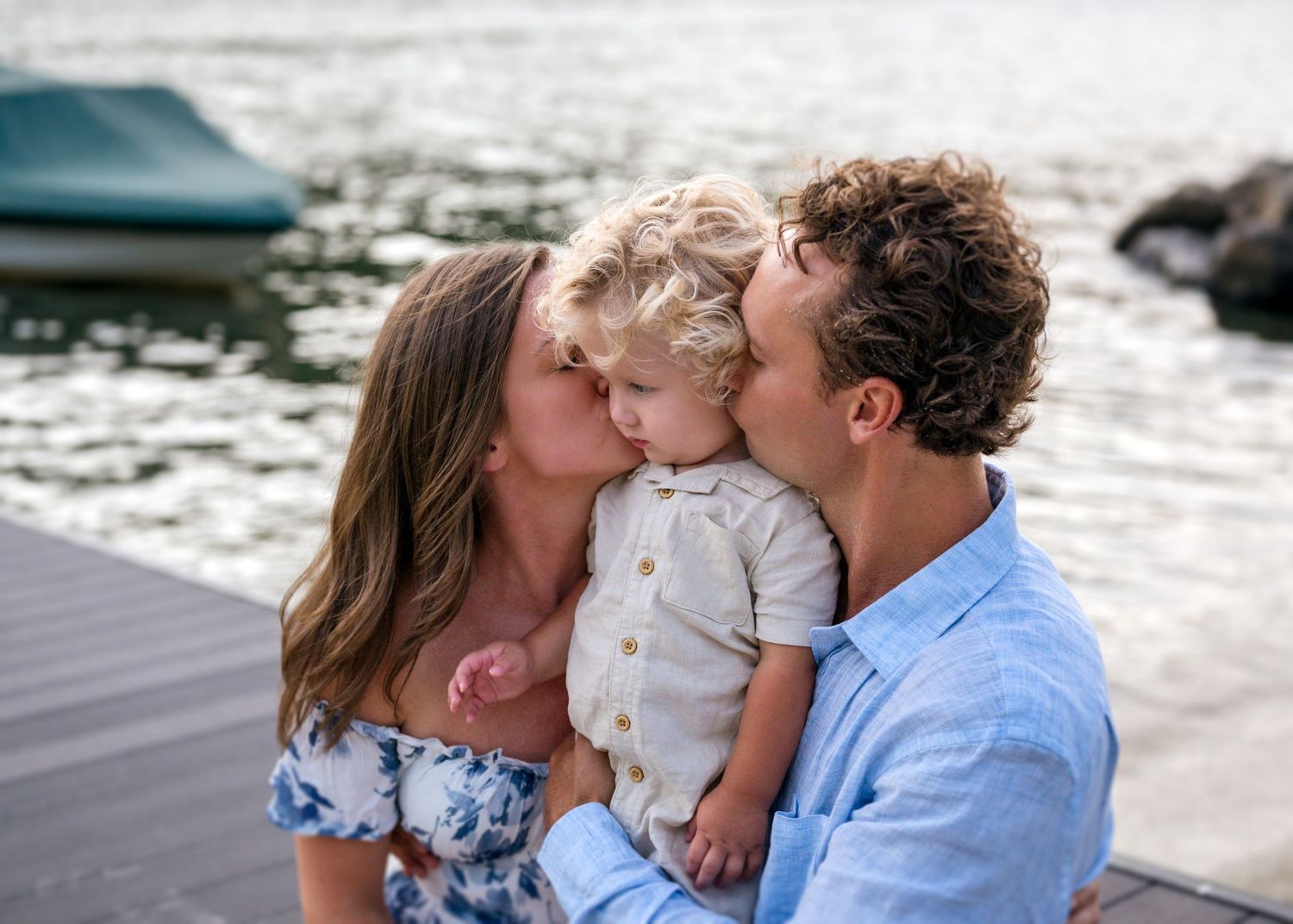 Family shares loving moment together by waterfront on sunny day.
