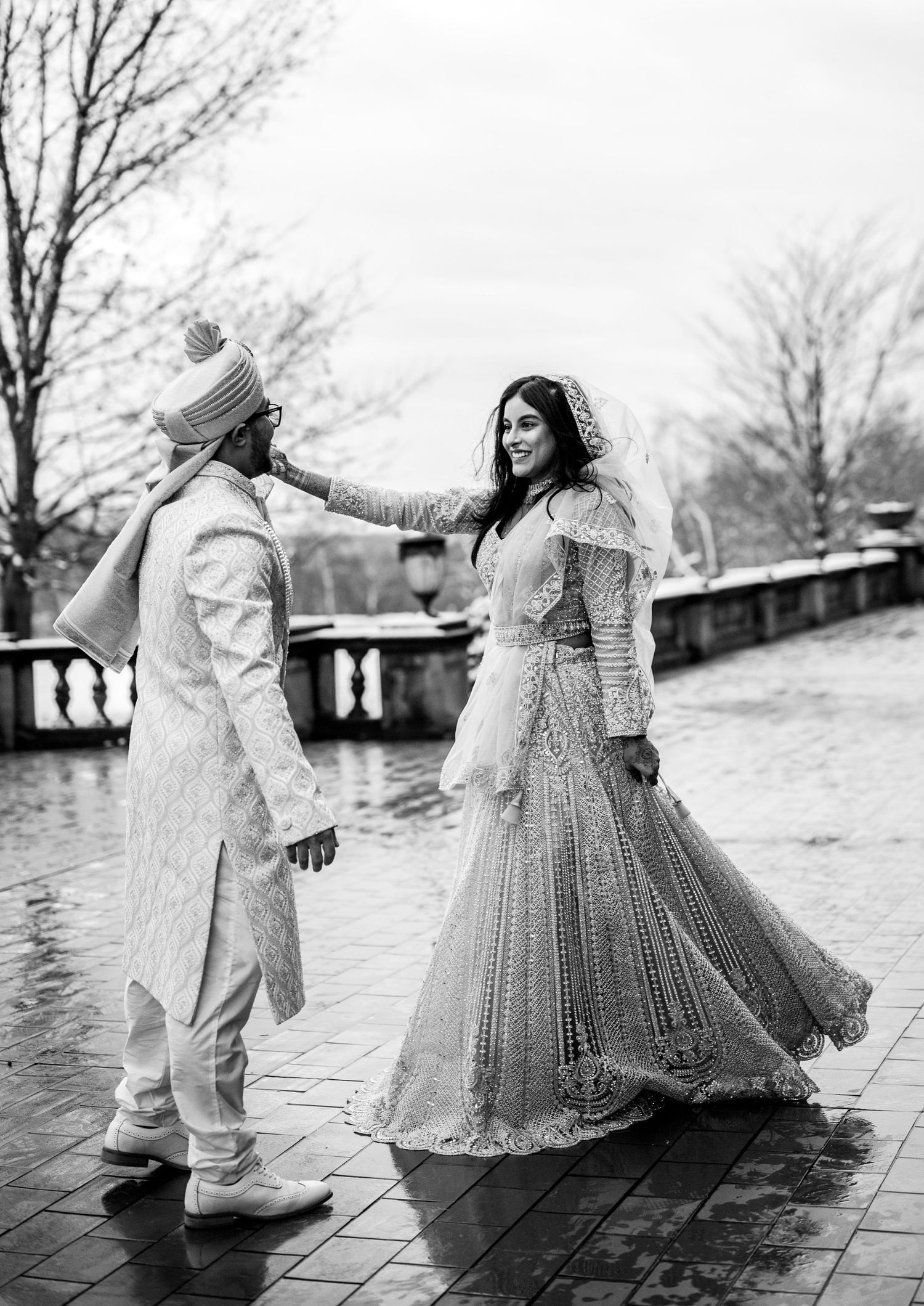 Dancing couple in flowing white outfits on a wet stone patio.
