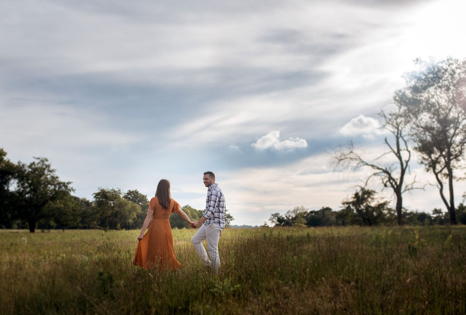 Panoramic landscape shots of a couple walking through a sunny meadow.
