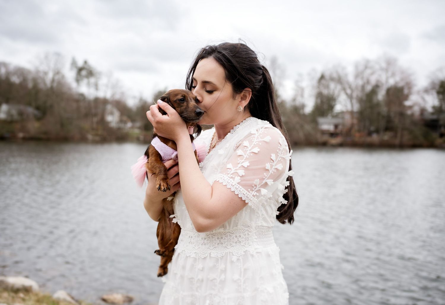 Romantic lakeside wedding portraits with water and trees in background.