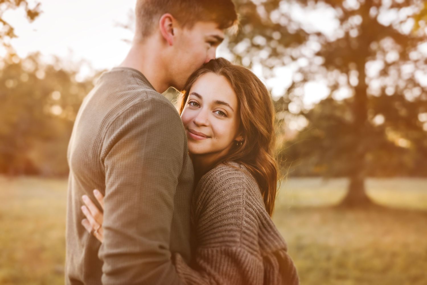 Romantic autumn engagement photos in field during golden hour.