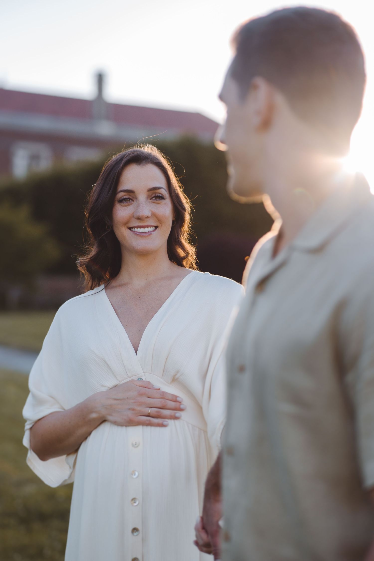 A couple shares intimate moments in a sunlit field during a golden hour photoshoot.