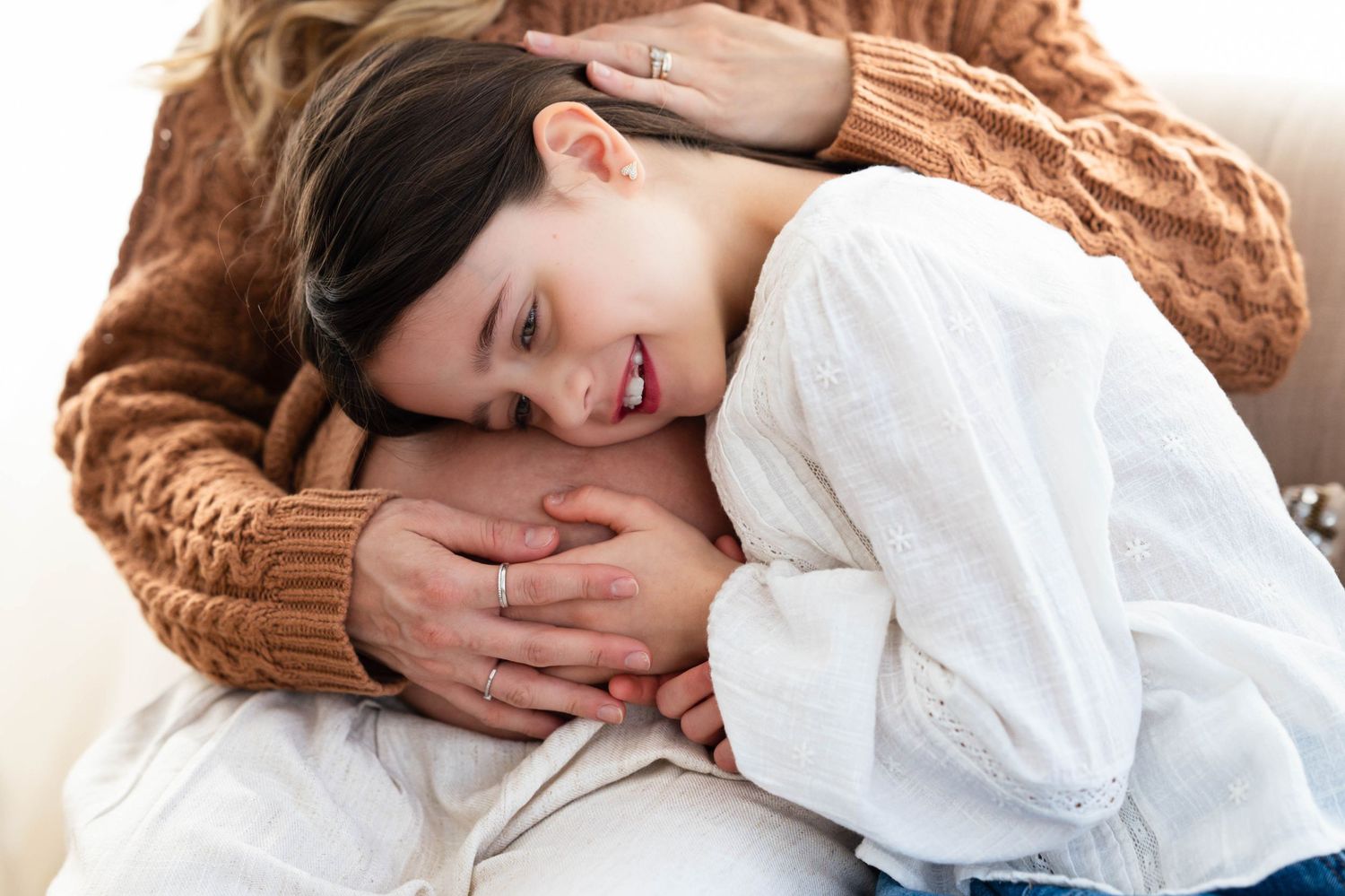 Someone lying on white bedding with long brown hair spread out on the pillow while resting.