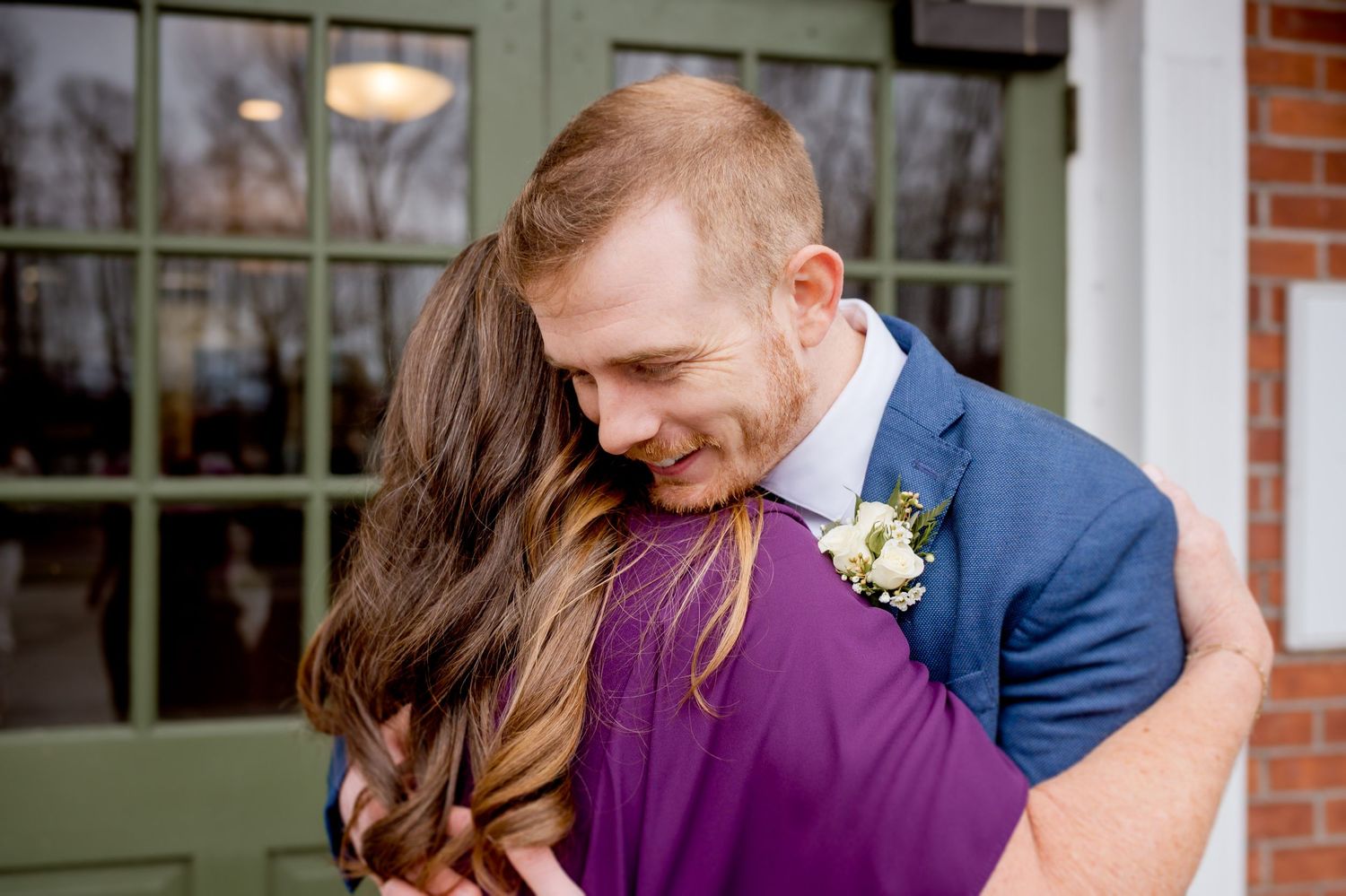 Wedding couple sharing a romantic moment against a green door backdrop.