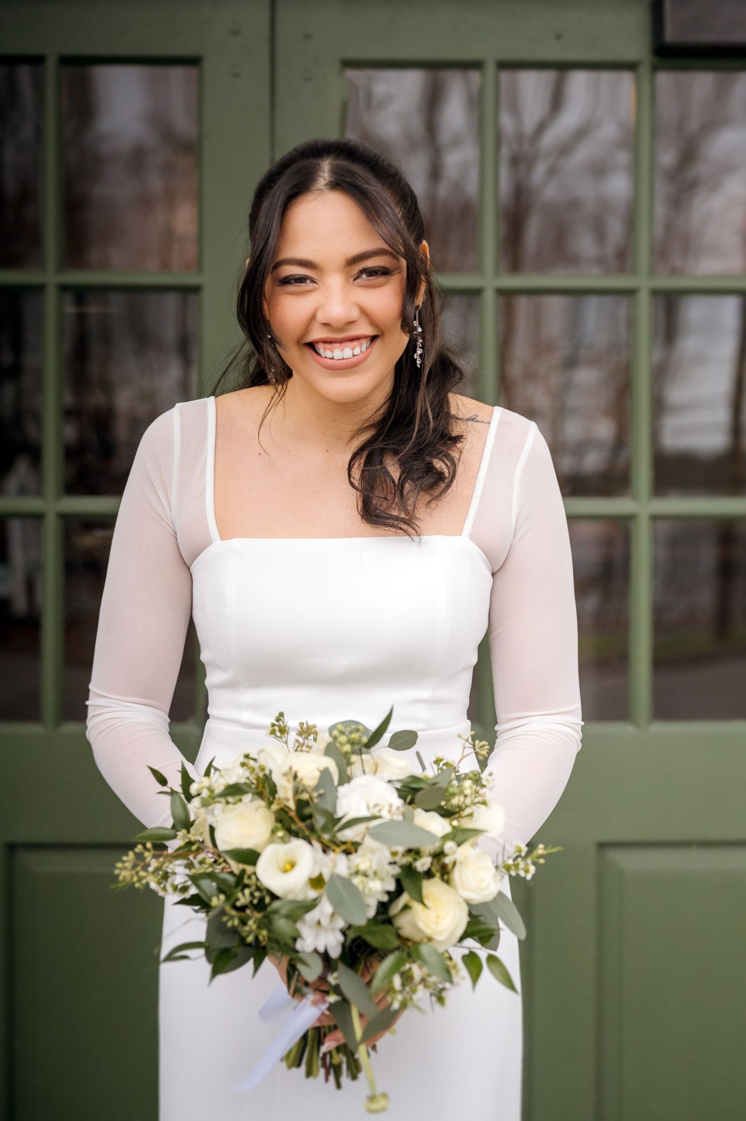 White floral bouquet with green foliage in an elegant wedding setting.