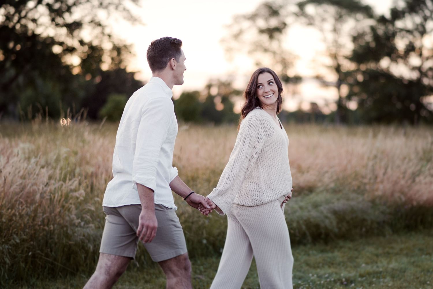 Tender moments captured between a couple in a rustic outdoor setting at dusk.
