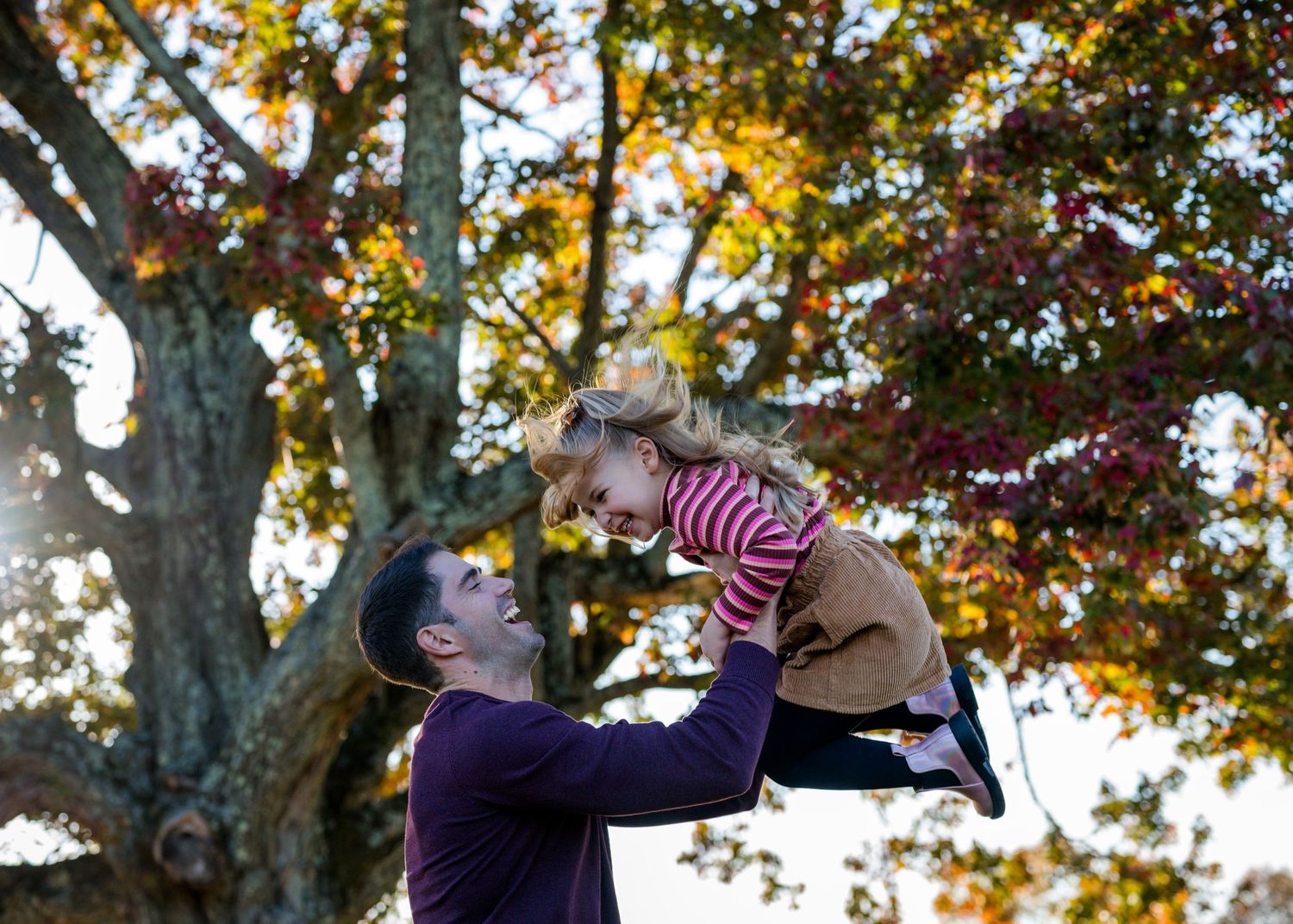 Family enjoying autumn moments together under colorful fall foliage.