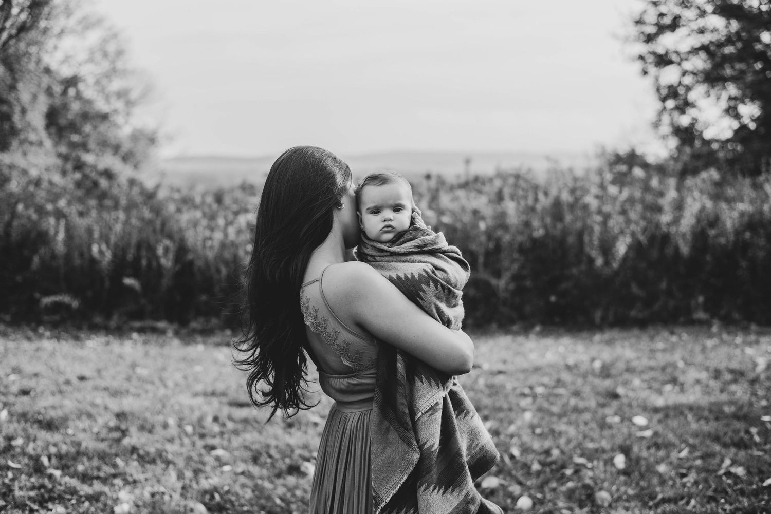 Black and white photo sequence showing a couple embracing in a romantic moment outdoors in a natural setting.