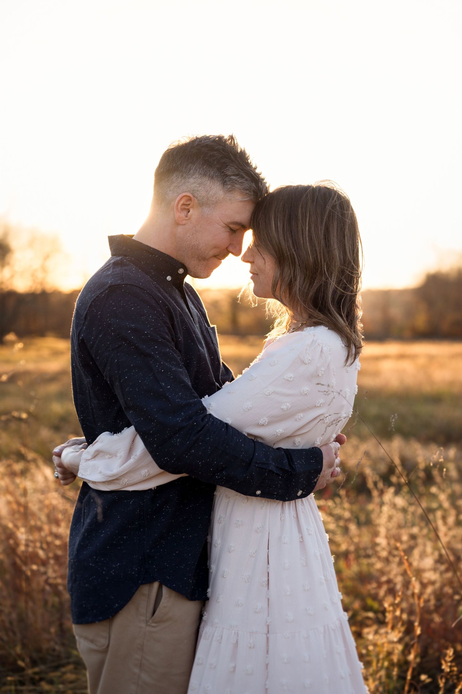 Romantic sunset photos of a couple embracing in a golden field.